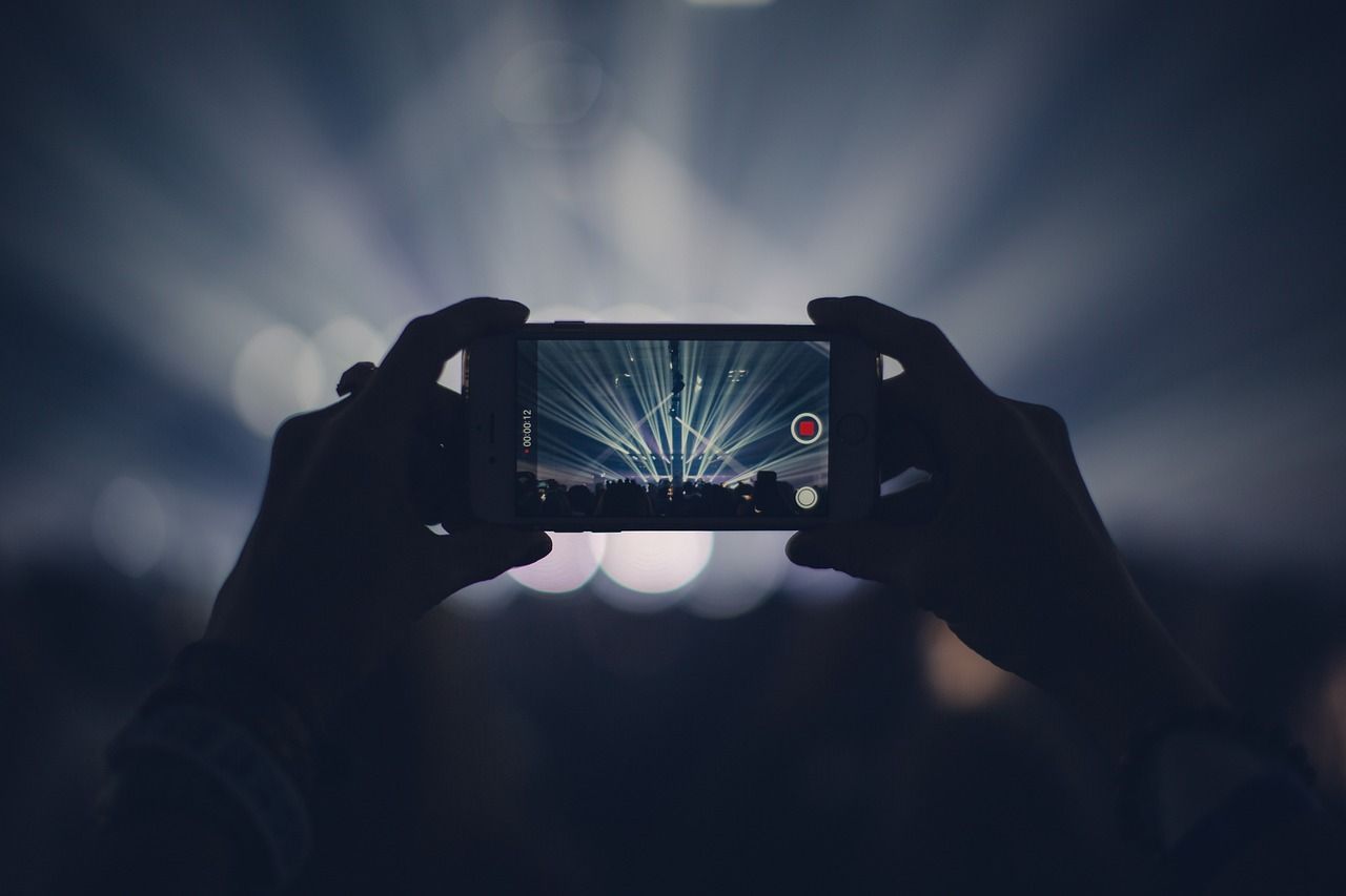 Concert audience holding up phones and lights during a live performance