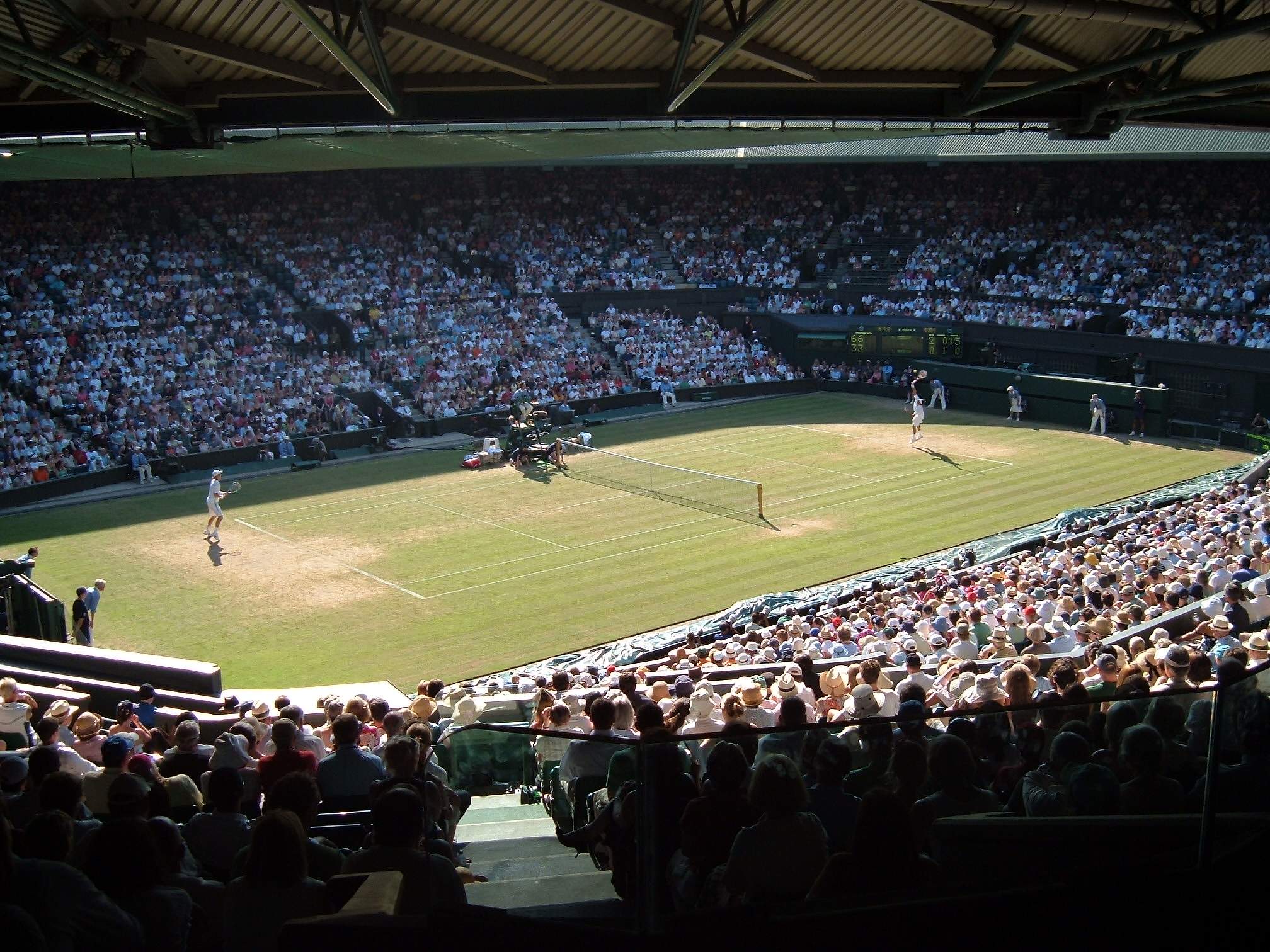 A match on one of Wimbledon's show courts, with the grass worn to bare soil behind each baseline