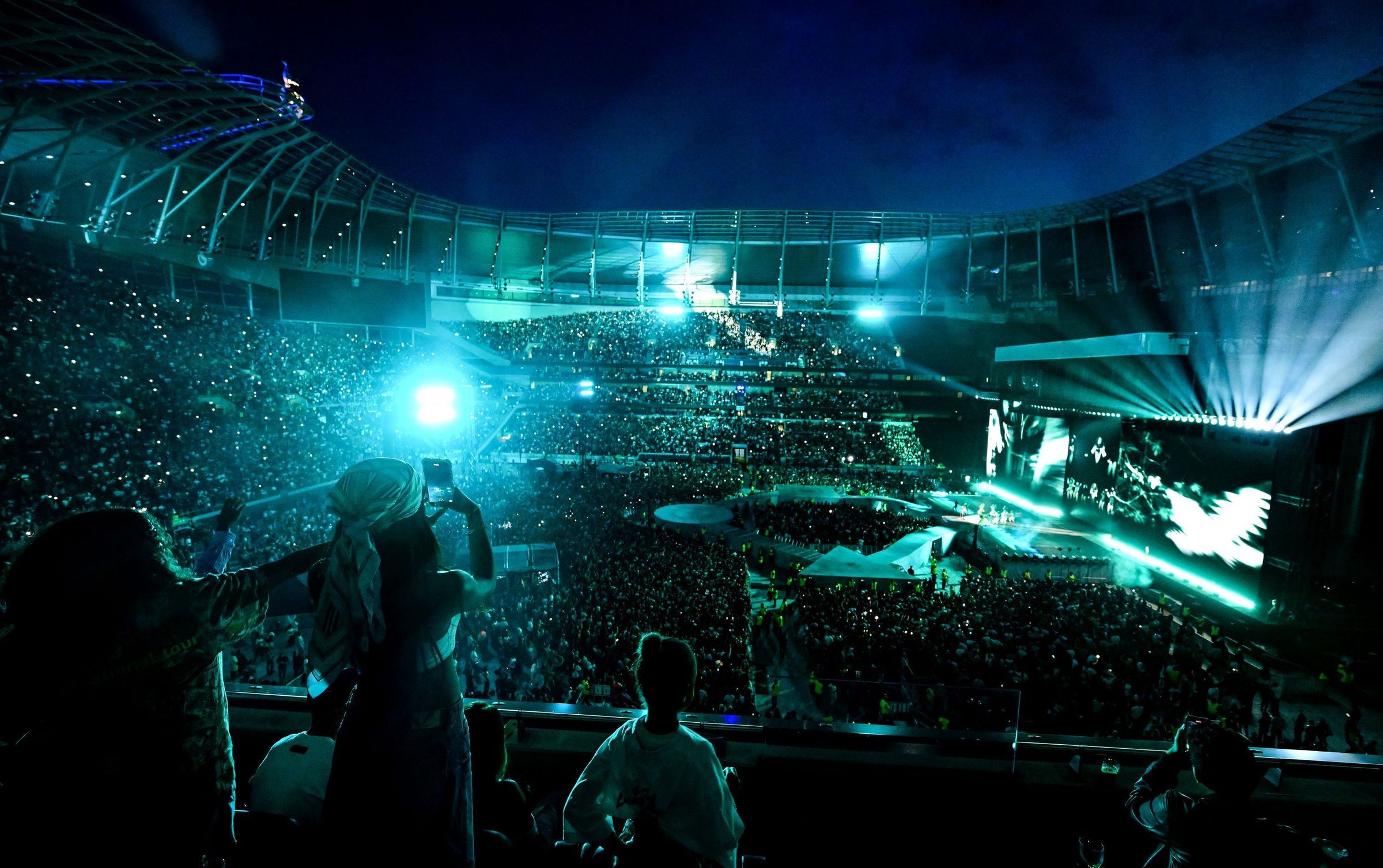 Photo for illustration: a concert at Tottenham Hotspur Stadium lit in teal, seen from the stands