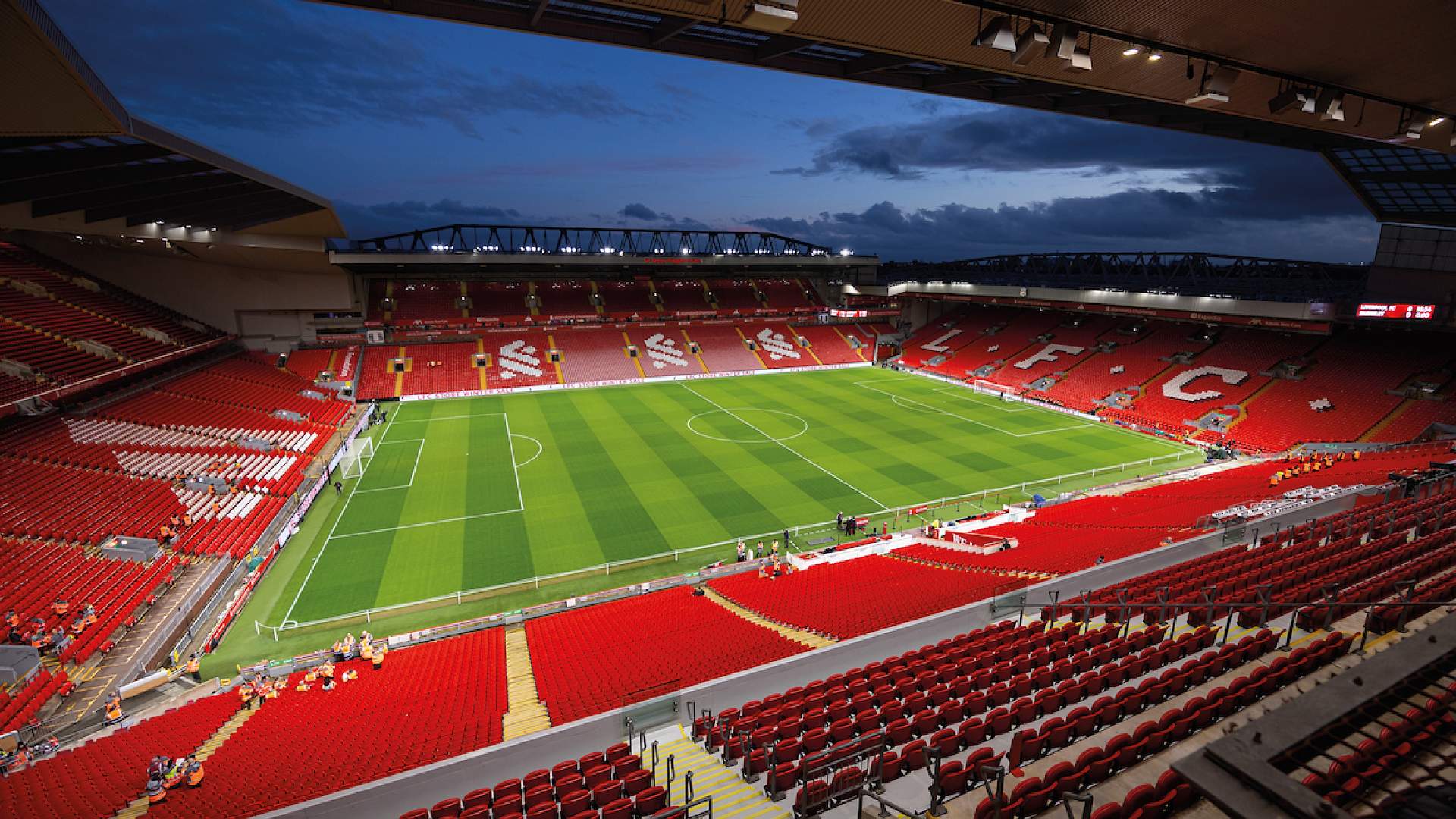 The empty Anfield bowl at dusk, seen from high in the stands with the floodlights on