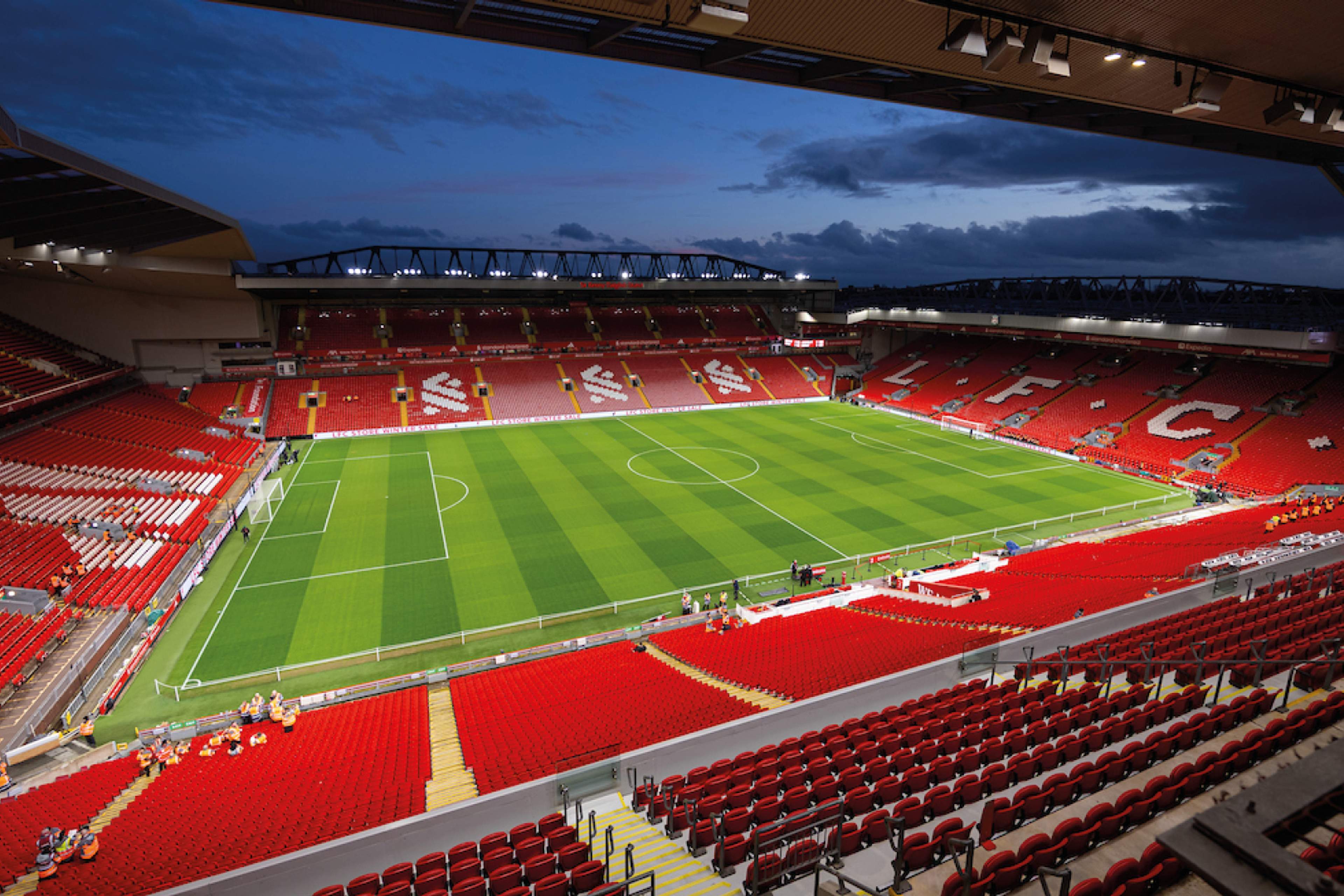 The empty Anfield bowl at dusk, seen from high in the stands with the floodlights on