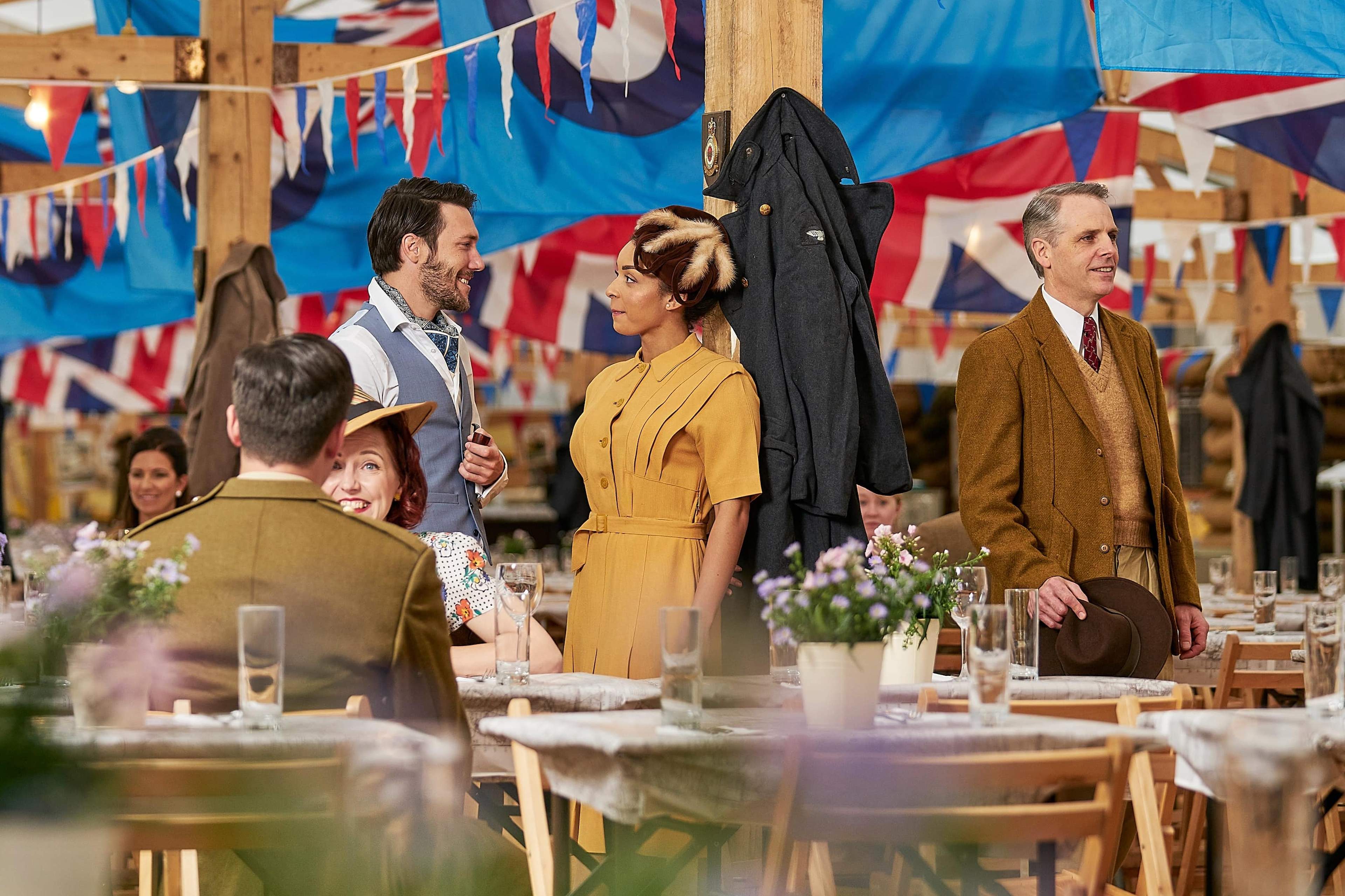 Guests in vintage clothing beside dining tables and bunting in Goodwood's Mess Pavilion