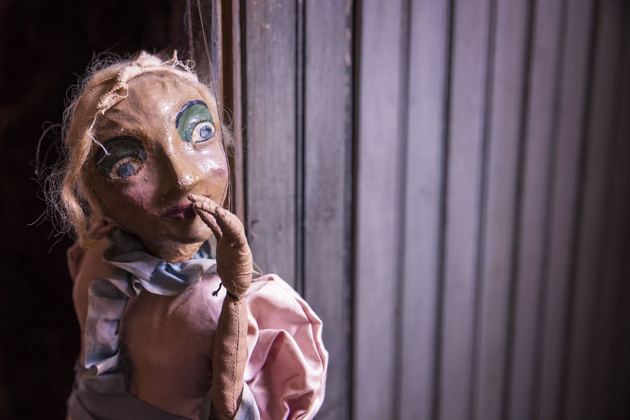Puppet on strings in a theatrical setting, evoking the puppet-driven storytelling of Avenue Q