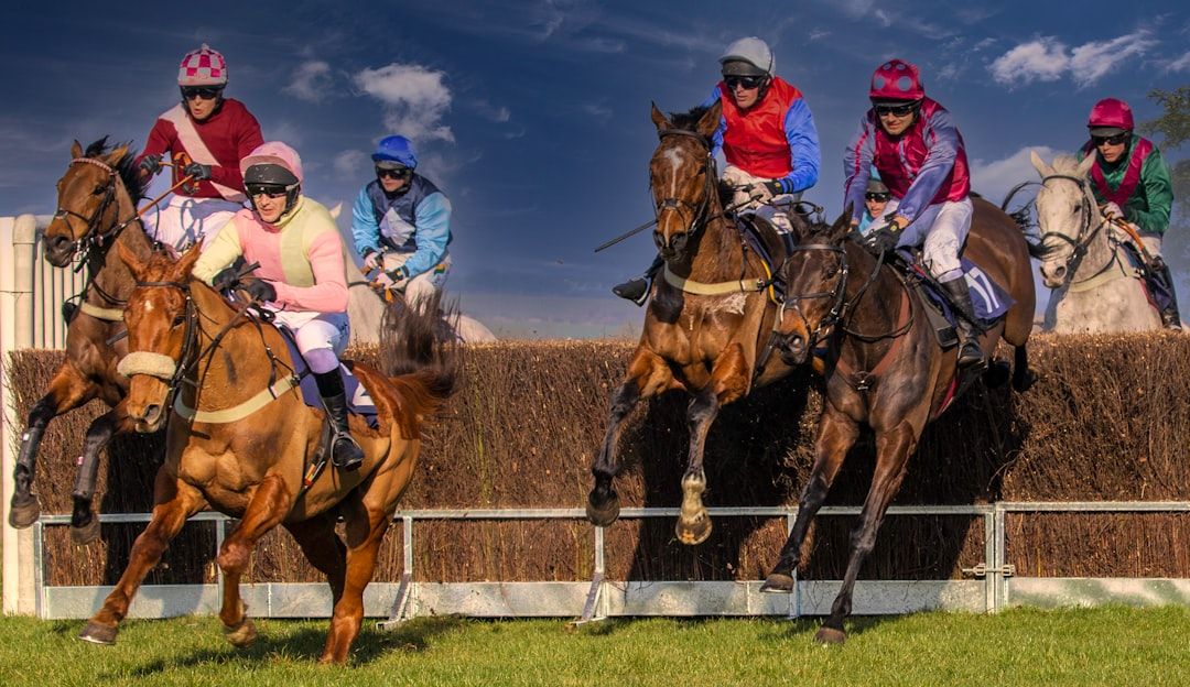 Two horses and jockeys racing side by side during a jump race