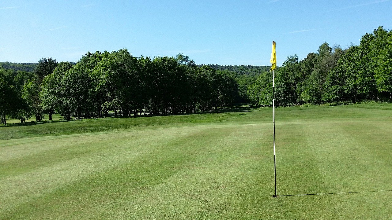 Scenic golf course fairway with flag and green under blue sky