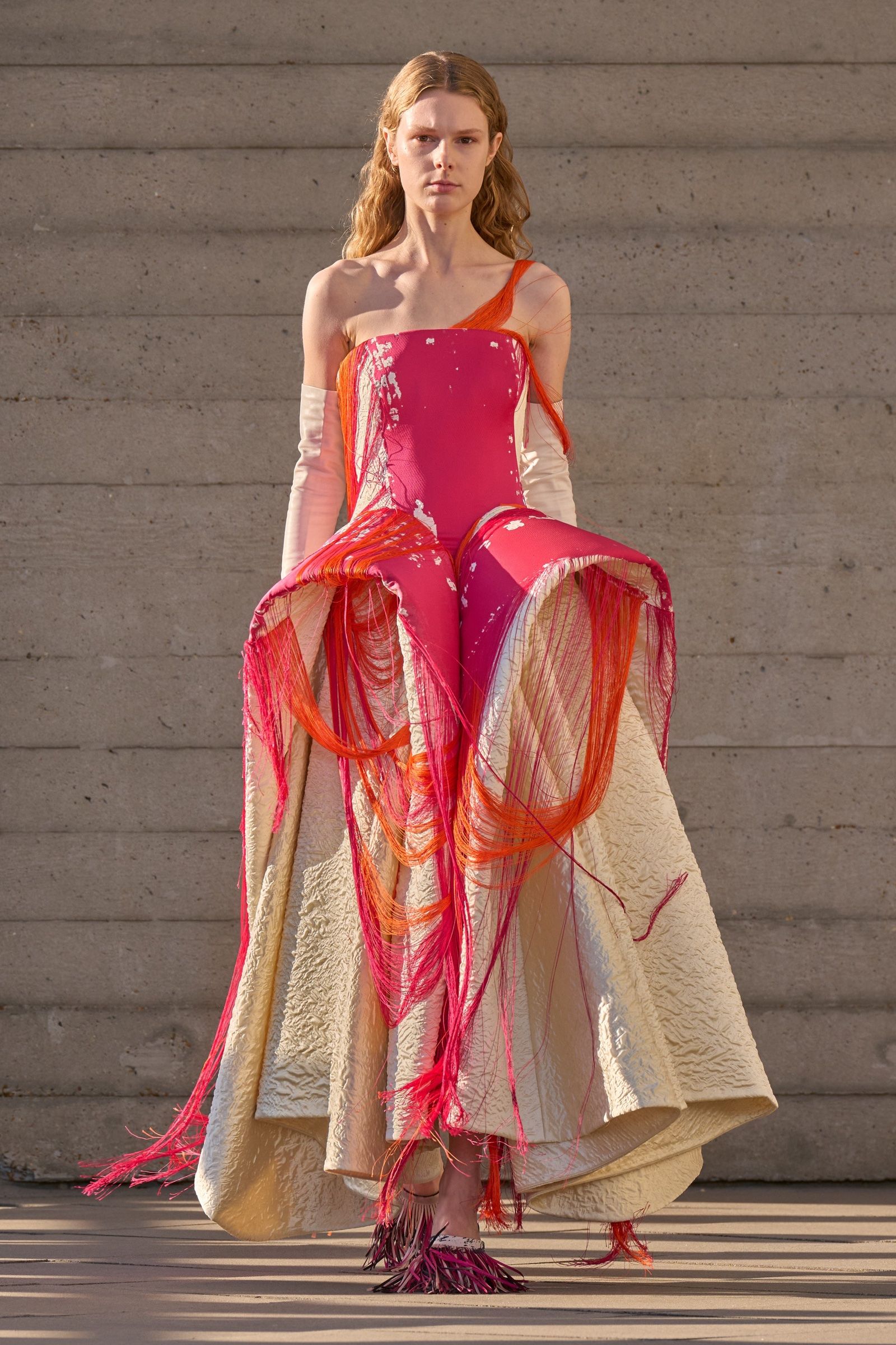 A pink corseted dress trailing pink and orange threads over a full cream skirt, from Roksanda's September 2026 show