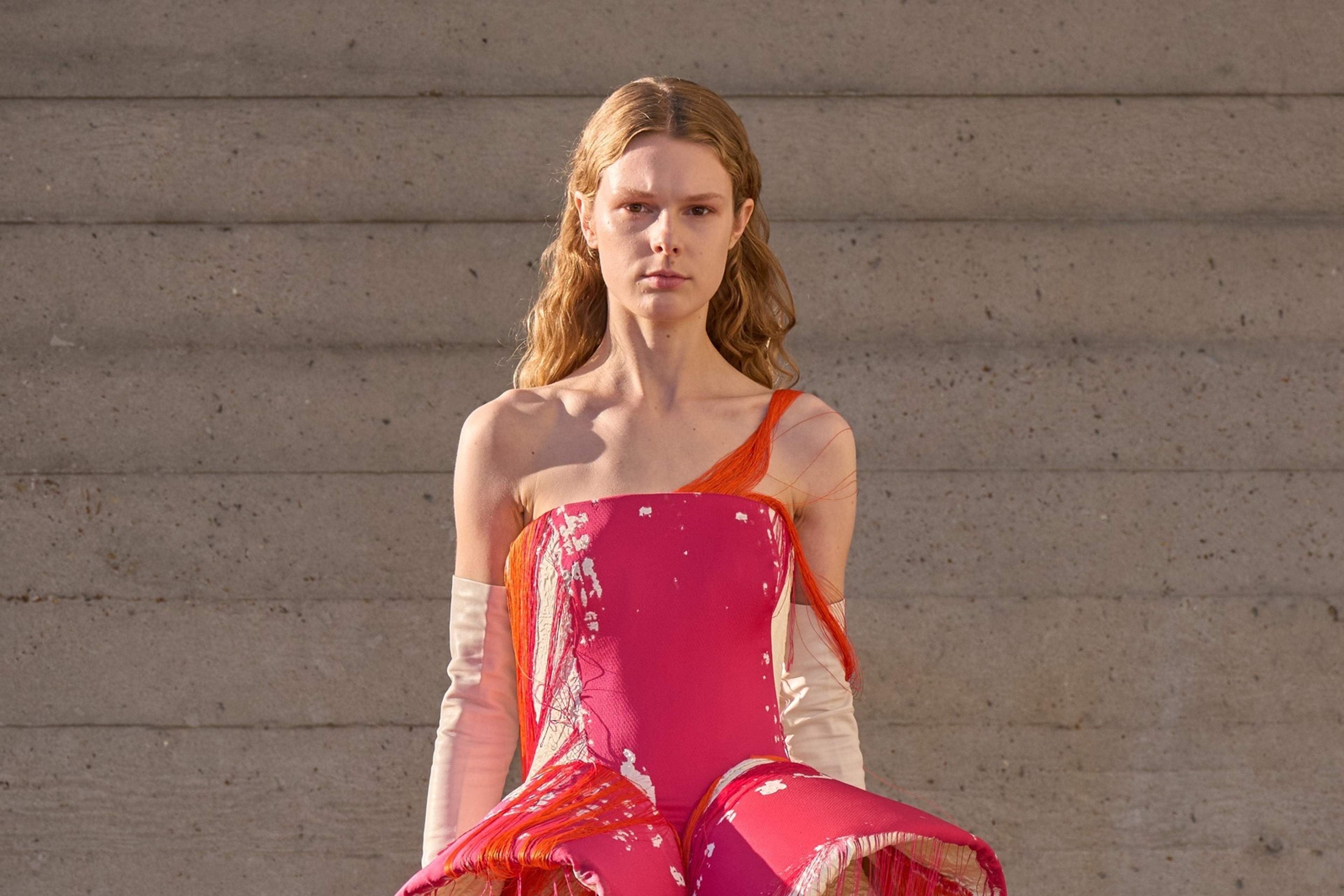 A pink corseted dress trailing pink and orange threads over a full cream skirt, from Roksanda's September 2026 show