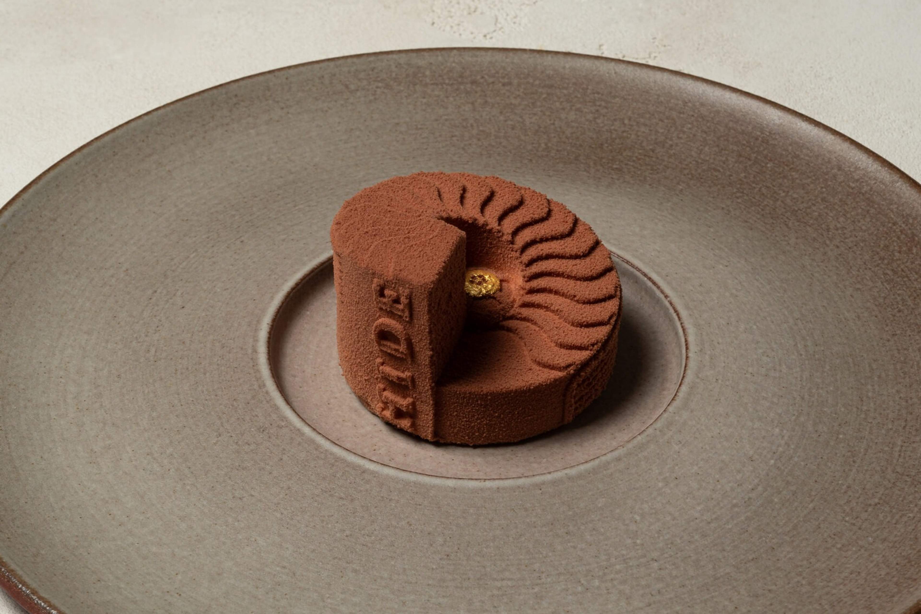 A chocolate dessert at HIDE, sculpted like the restaurant's spiral oak staircase and stamped with its name, on a wide grey plate