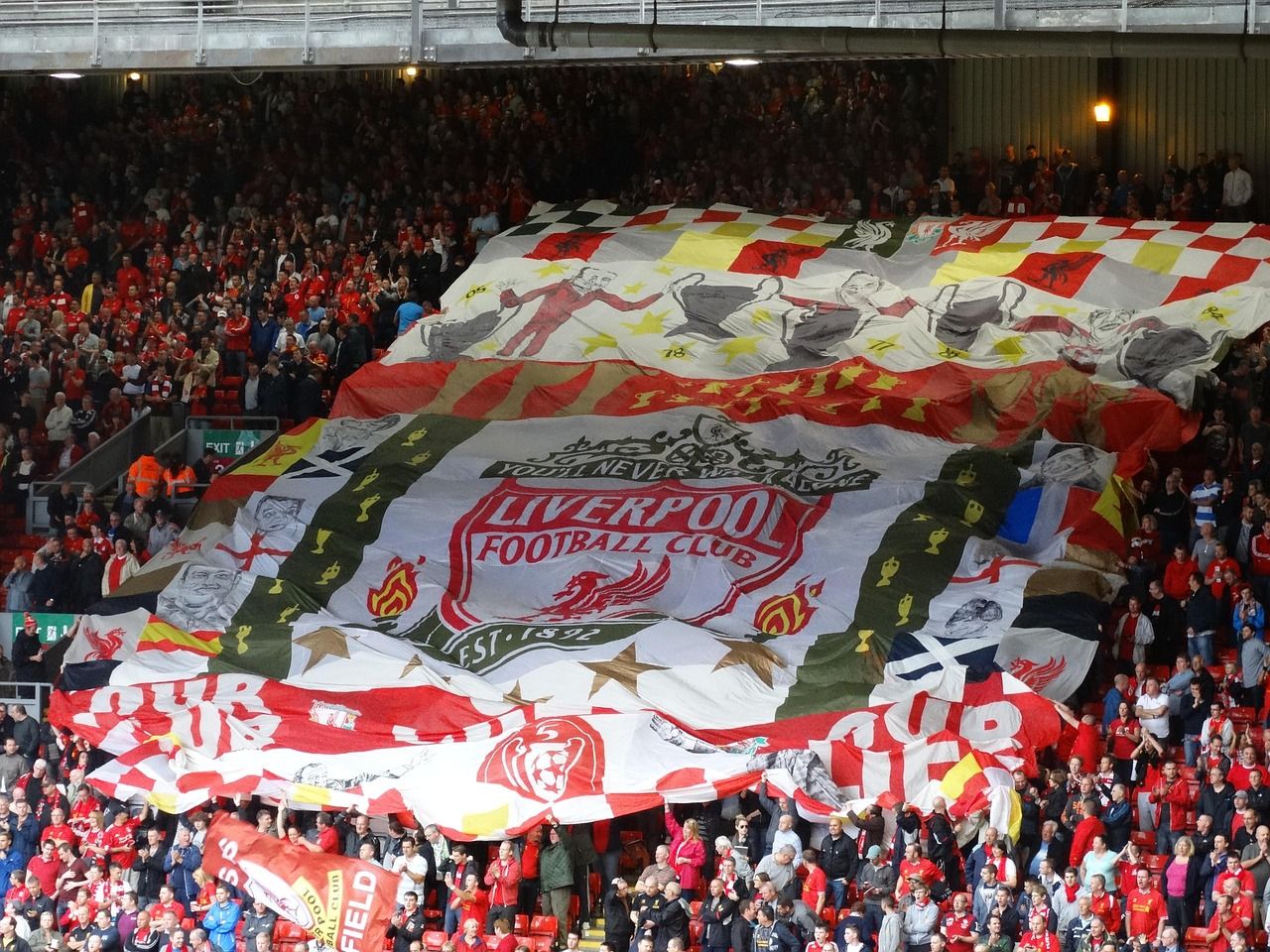 Liverpool fans at Anfield with a large flag draped across the Kop