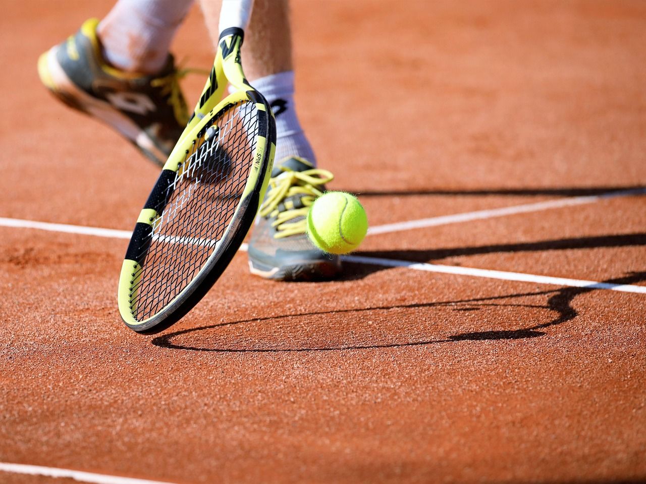 Tennis ball and racket on a grass court, evoking the early days of the sport