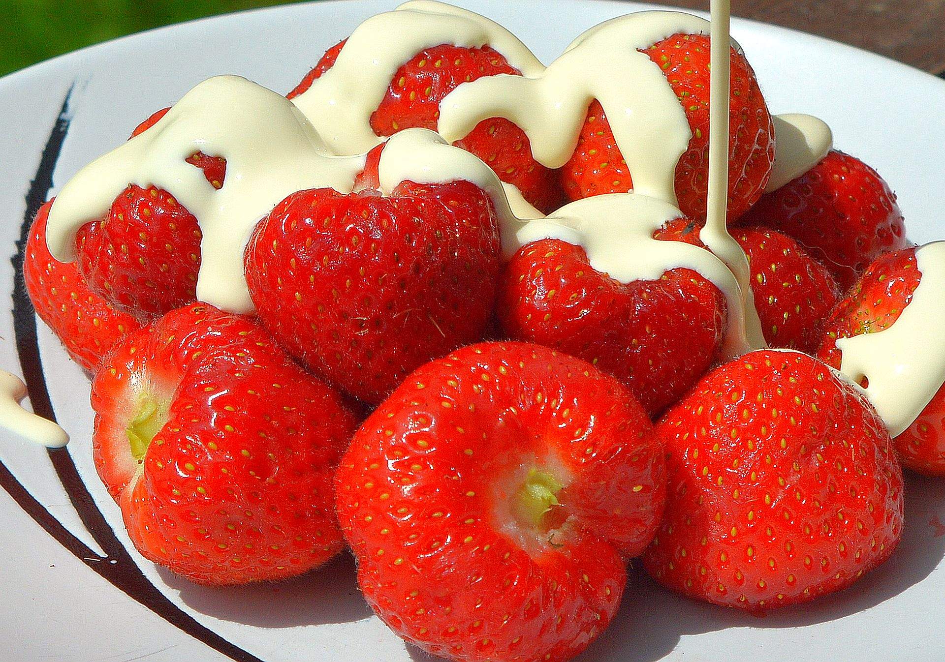 Fresh strawberries with cream poured over them in the sun