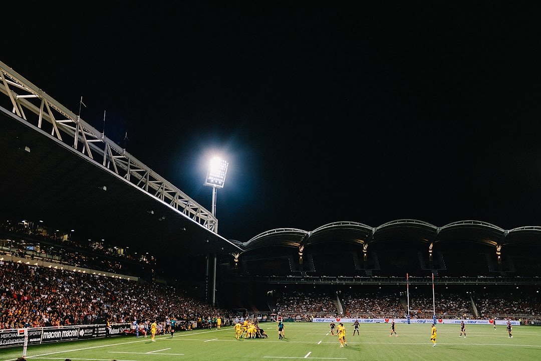 Rugby match being played in a stadium at night under floodlights