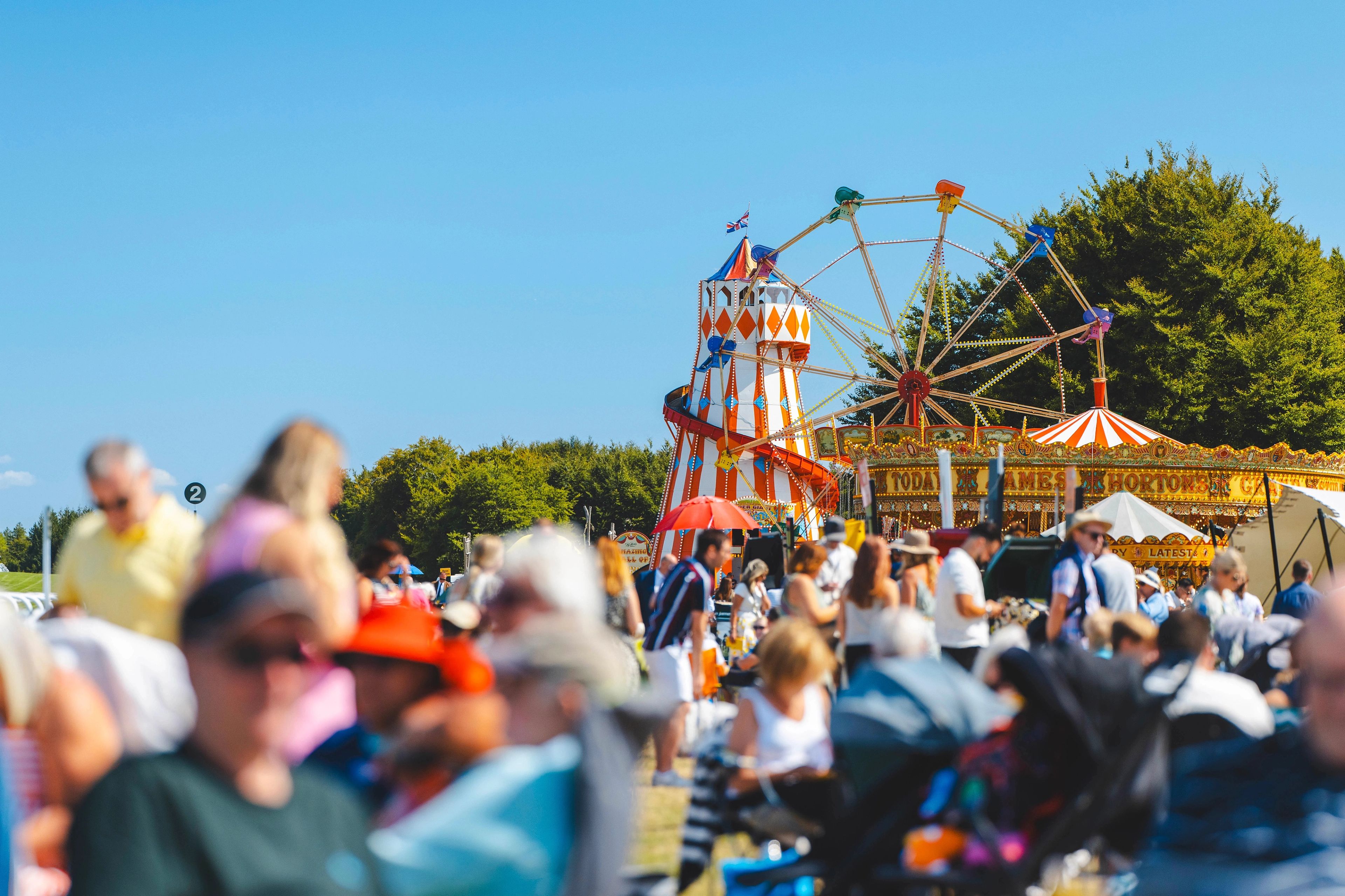 Spectators in summer dress at Goodwood racecourse, enjoying a sunny day at the iconic British sporting venue.