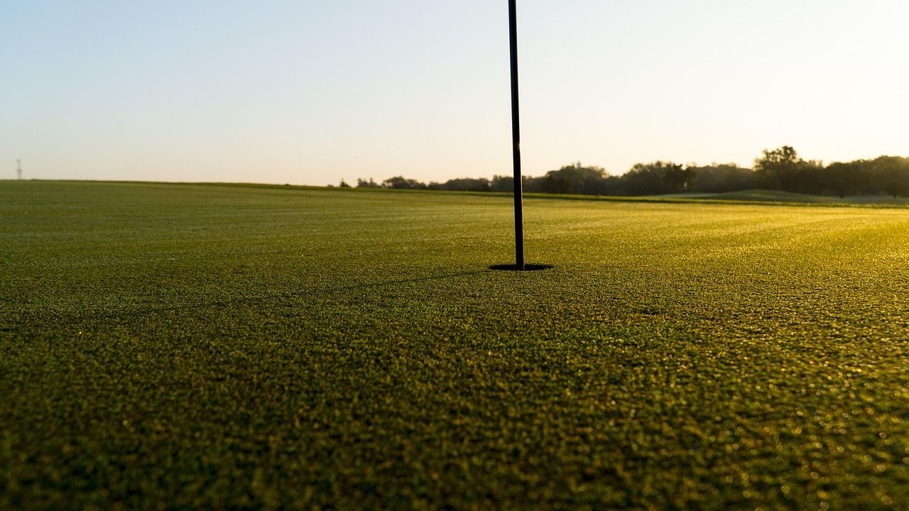 Golfers on a lush green golf course with rolling landscape
