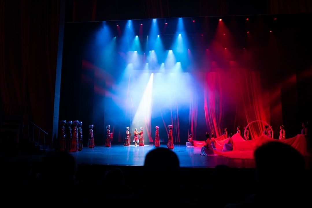 Dancers performing on a grand theatre stage with dramatic red and blue lighting