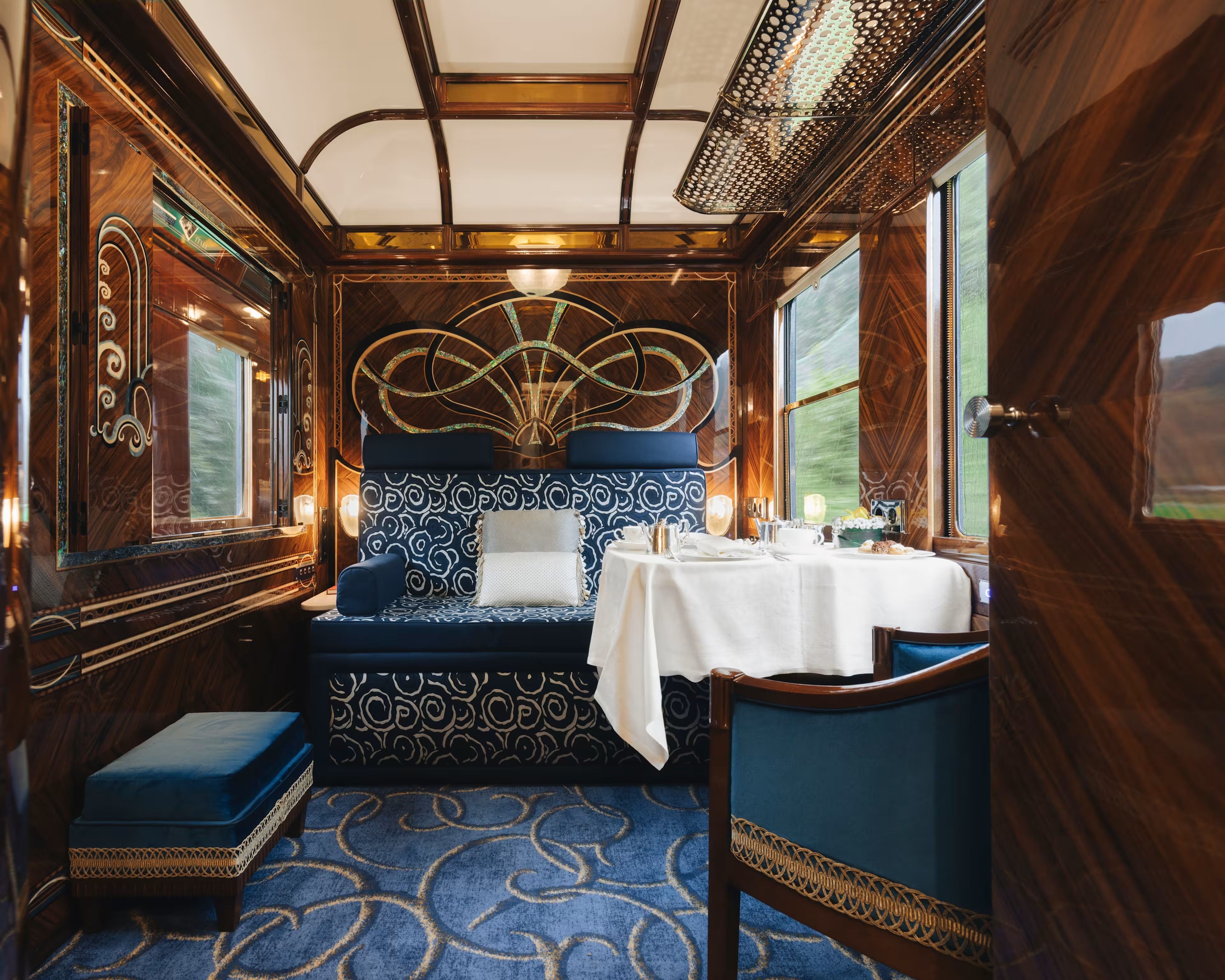 Suite in its day configuration, with a sofa beneath an inlaid Art Deco panel and a table laid for afternoon tea