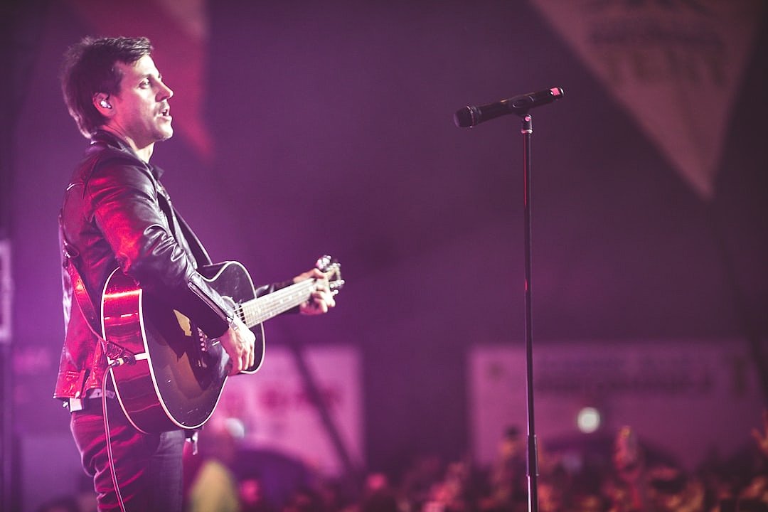 Guitarist standing alone on stage under spotlight