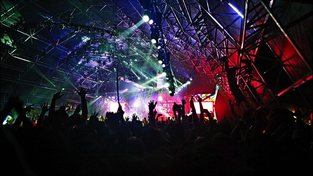Festival crowd silhouettes in front of a brightly lit stage