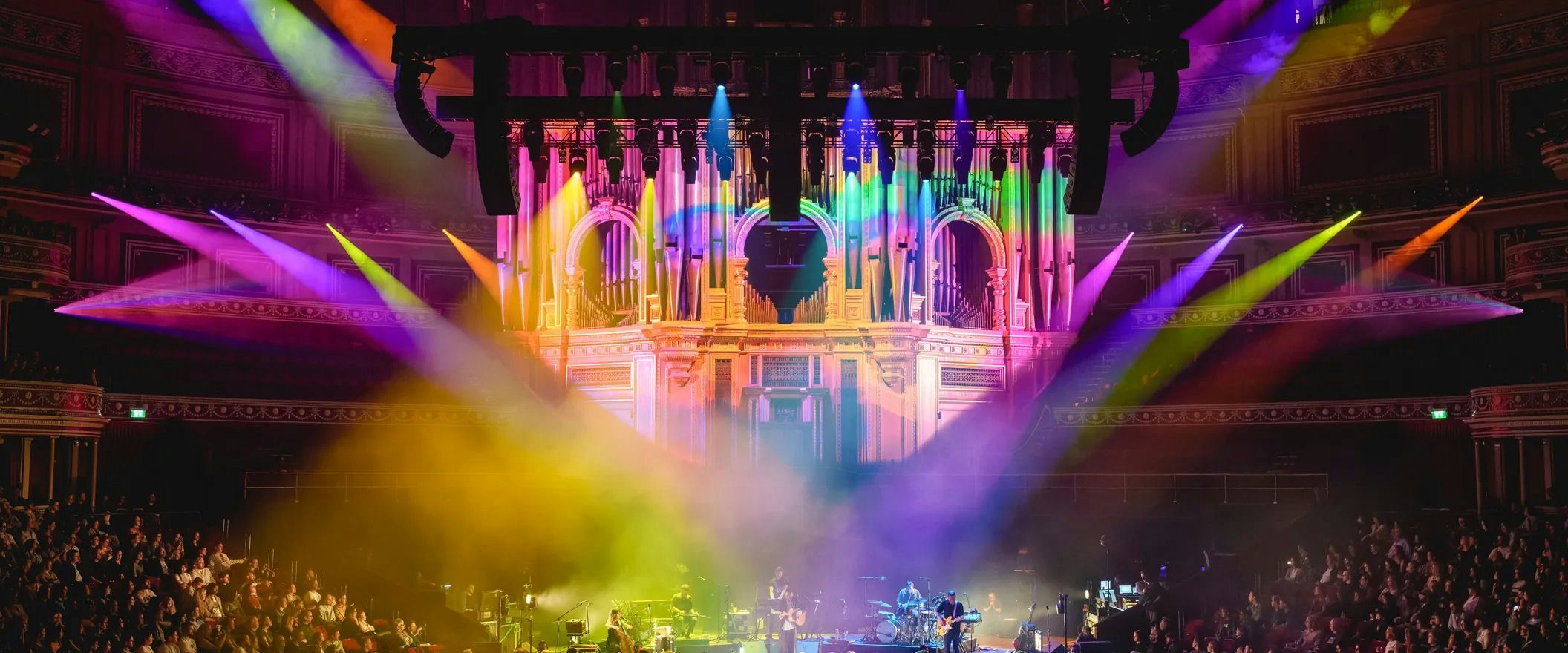 Beams of pink, yellow and green light sweeping across the stage and organ pipes inside the Royal Albert Hall during a concert