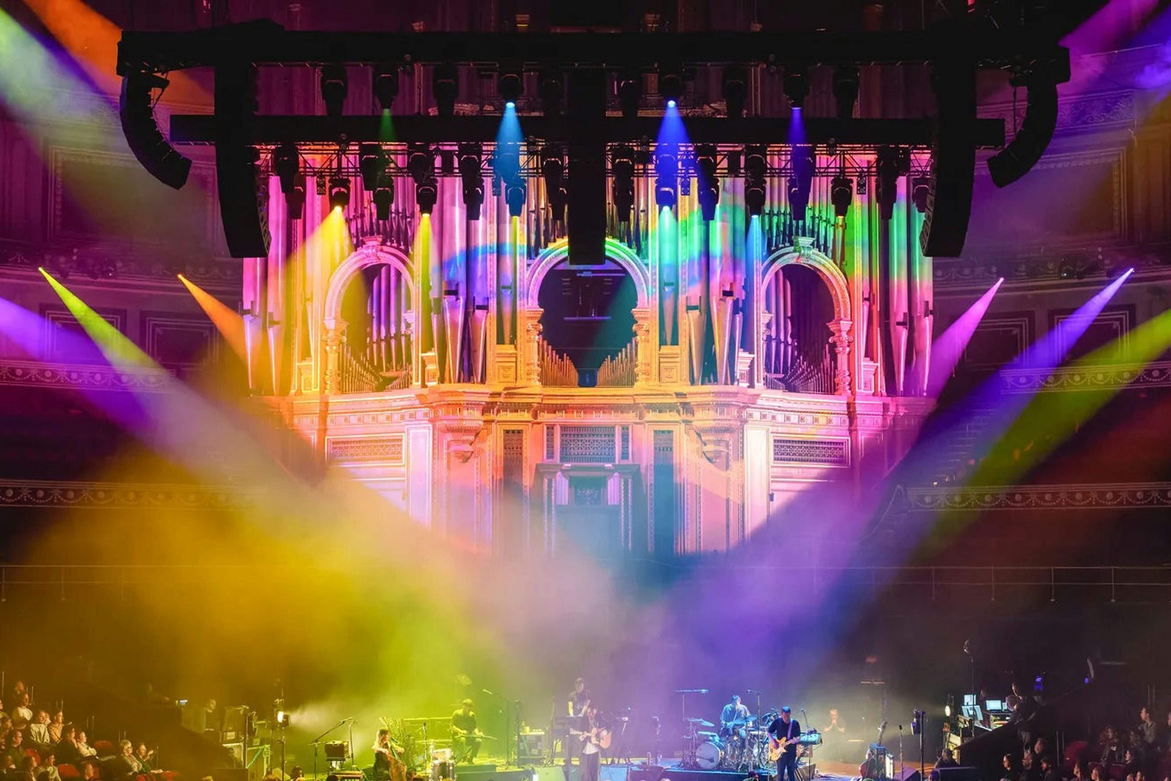 Beams of pink, yellow and green light sweeping across the stage and organ pipes inside the Royal Albert Hall during a concert