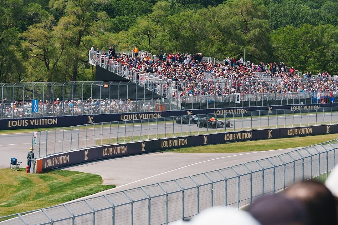 Formula 1 cars racing past packed grandstands with cheering spectators