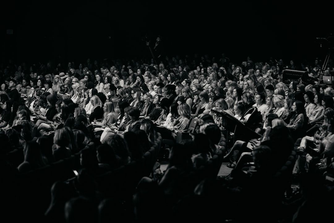 An audience watches a performance in a large arena venue