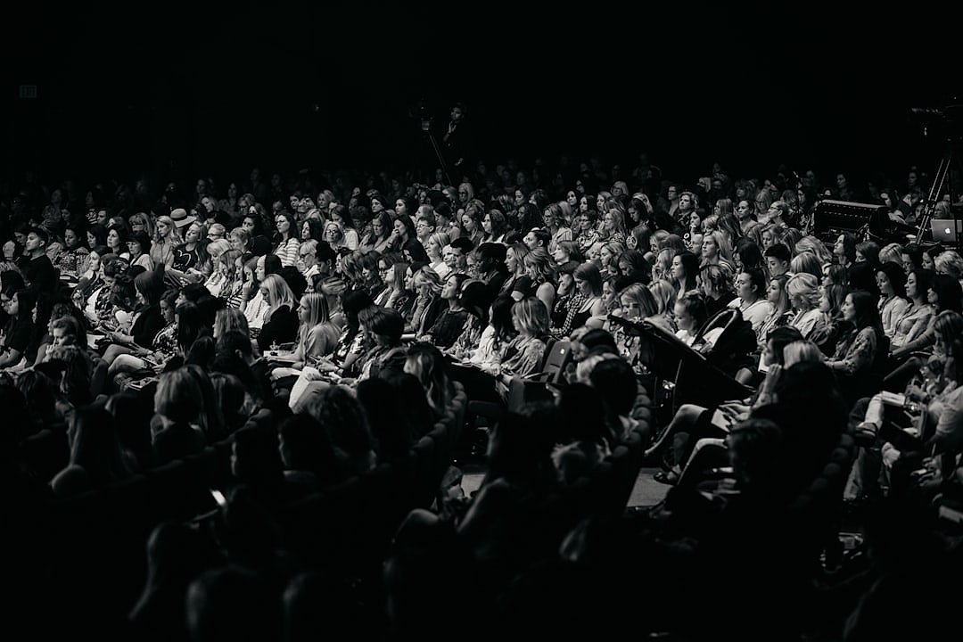 An audience watches a performance in a large arena venue
