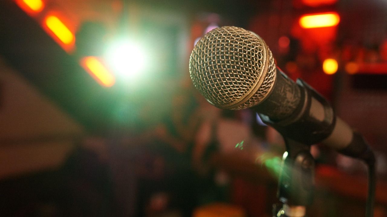 A spotlight illuminating a microphone on a comedy stage
