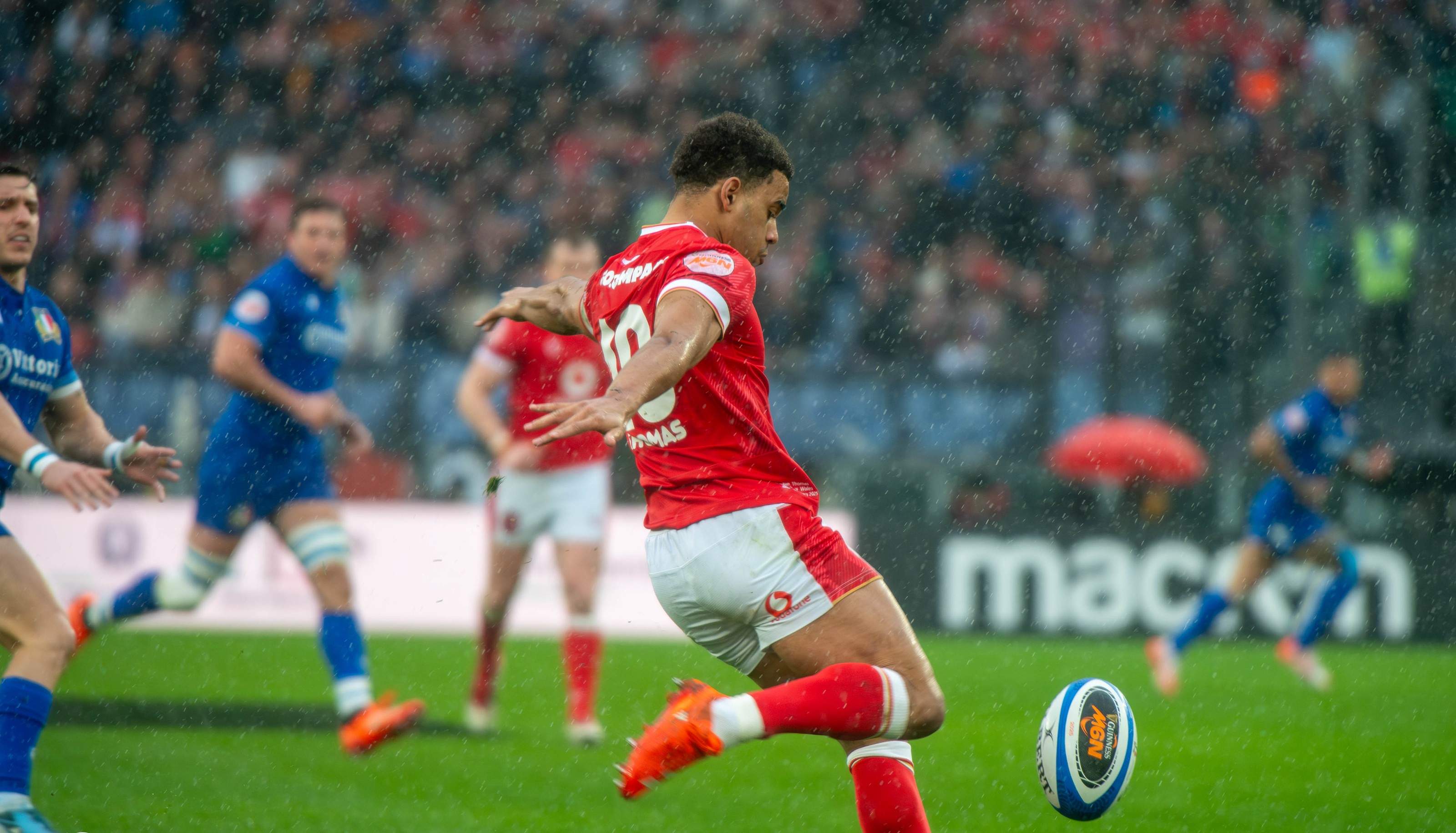A Wales player kicking at goal during Italy v Wales in the 2025 Six Nations, with the crowd in the stand behind him