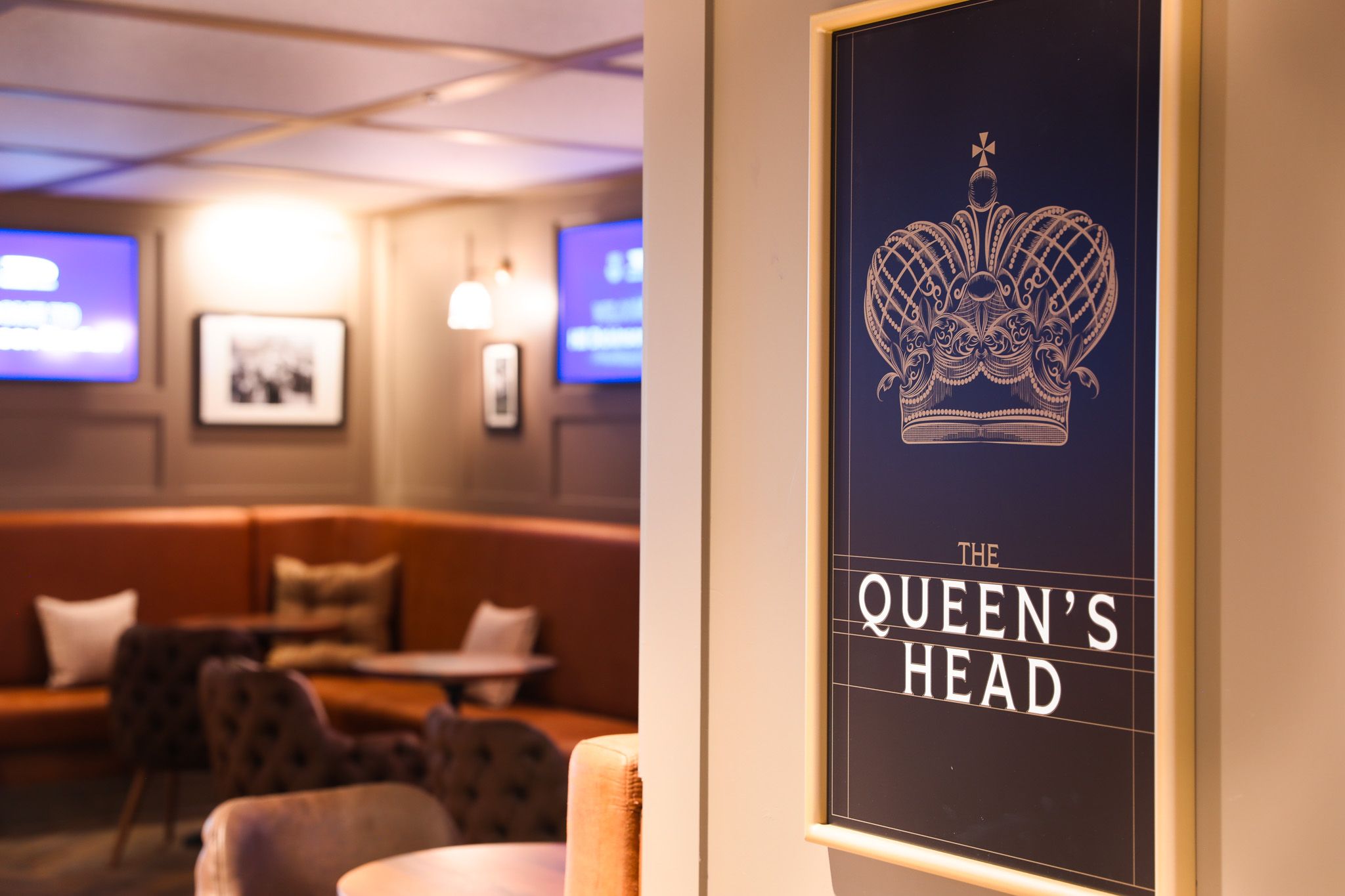 Village Street, Hill Dickinson Stadium: The Queen's Head illuminated pub sign with lounge seating behind