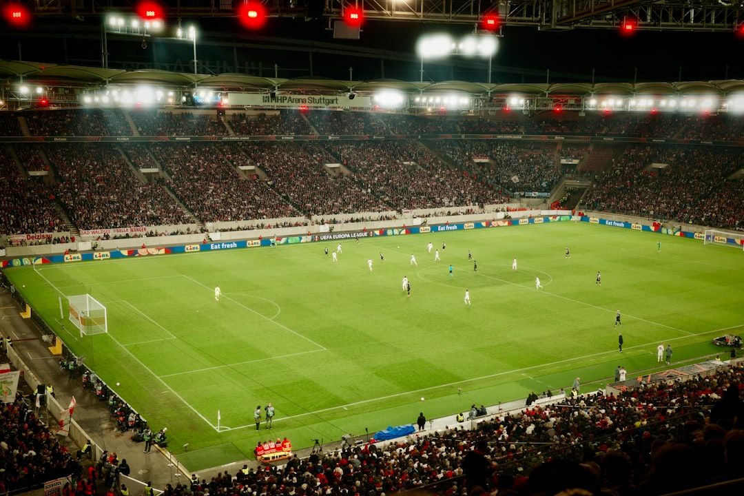 Football match played under floodlights at a packed stadium at night