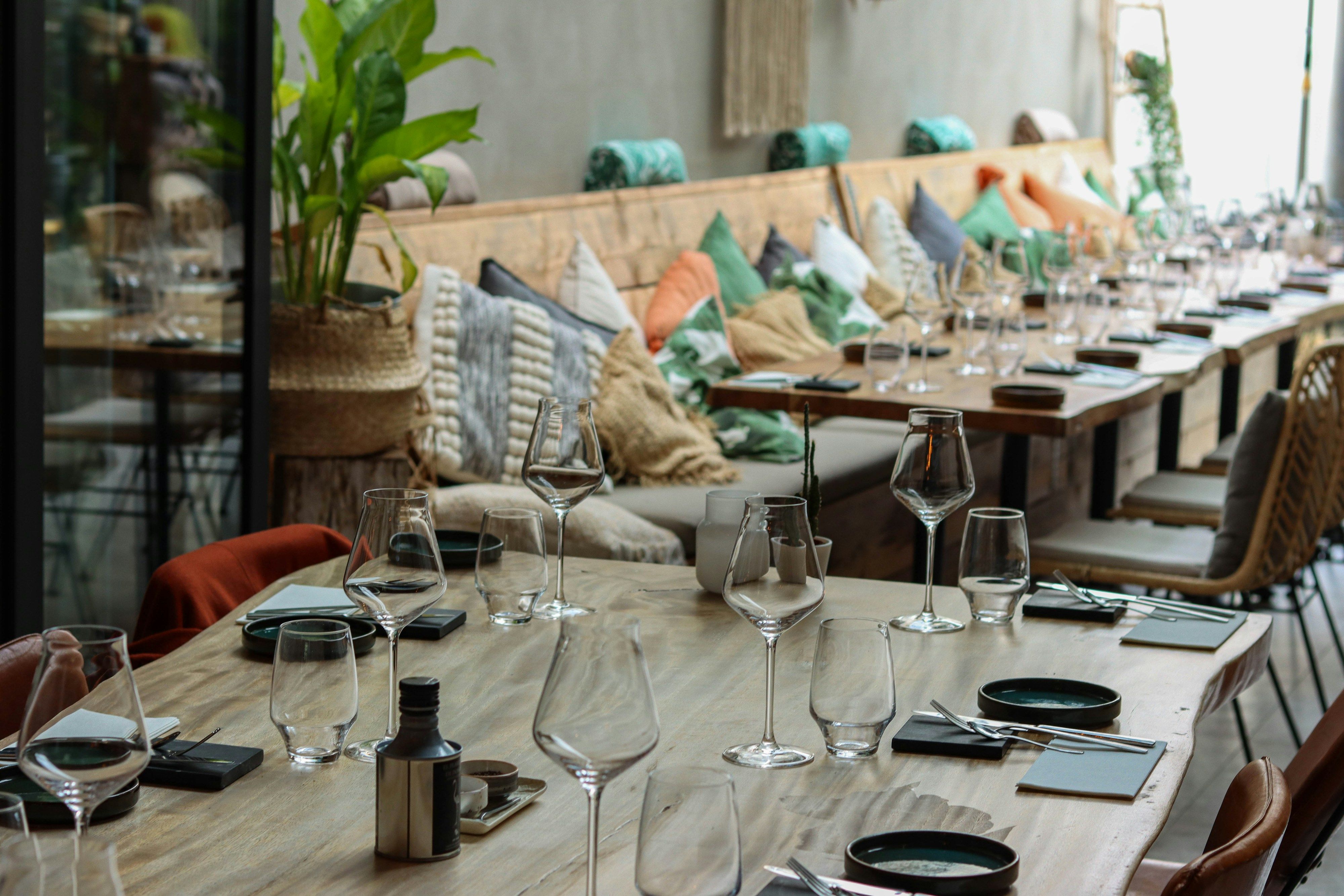 Long restaurant table set with wine glasses and place settings