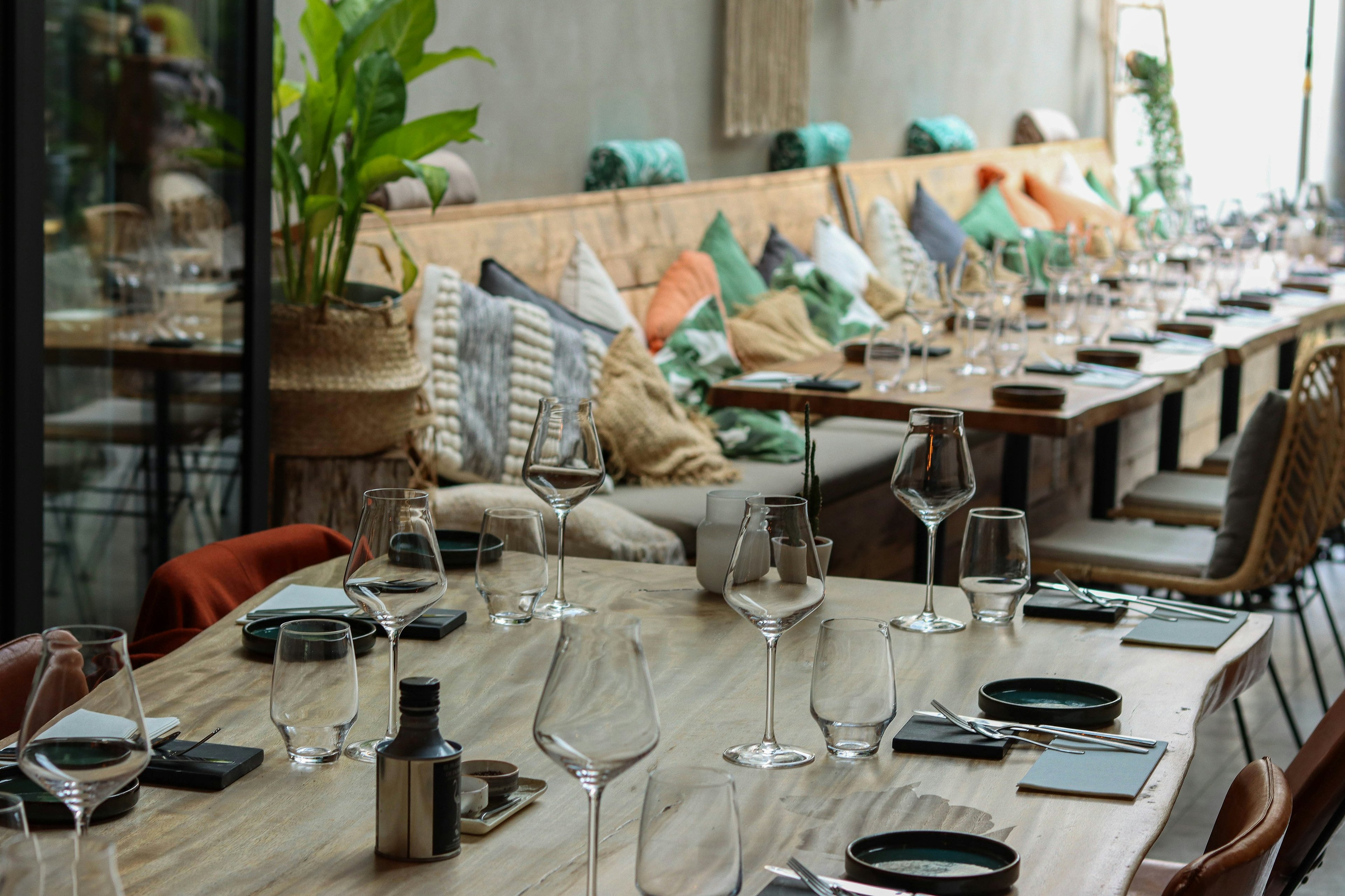 Long restaurant table set with wine glasses and place settings
