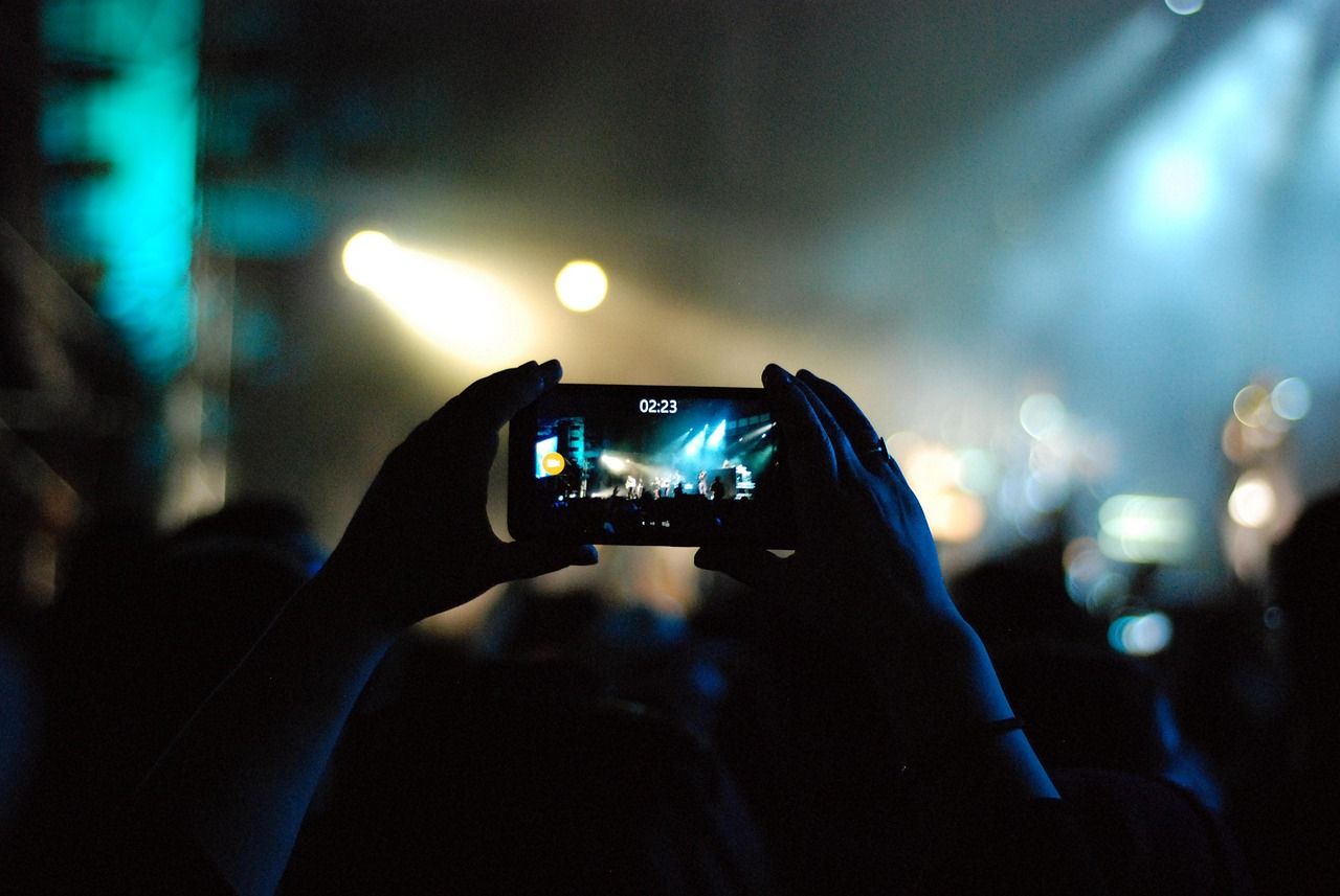 Concert crowd holding up smartphones to record a live performance