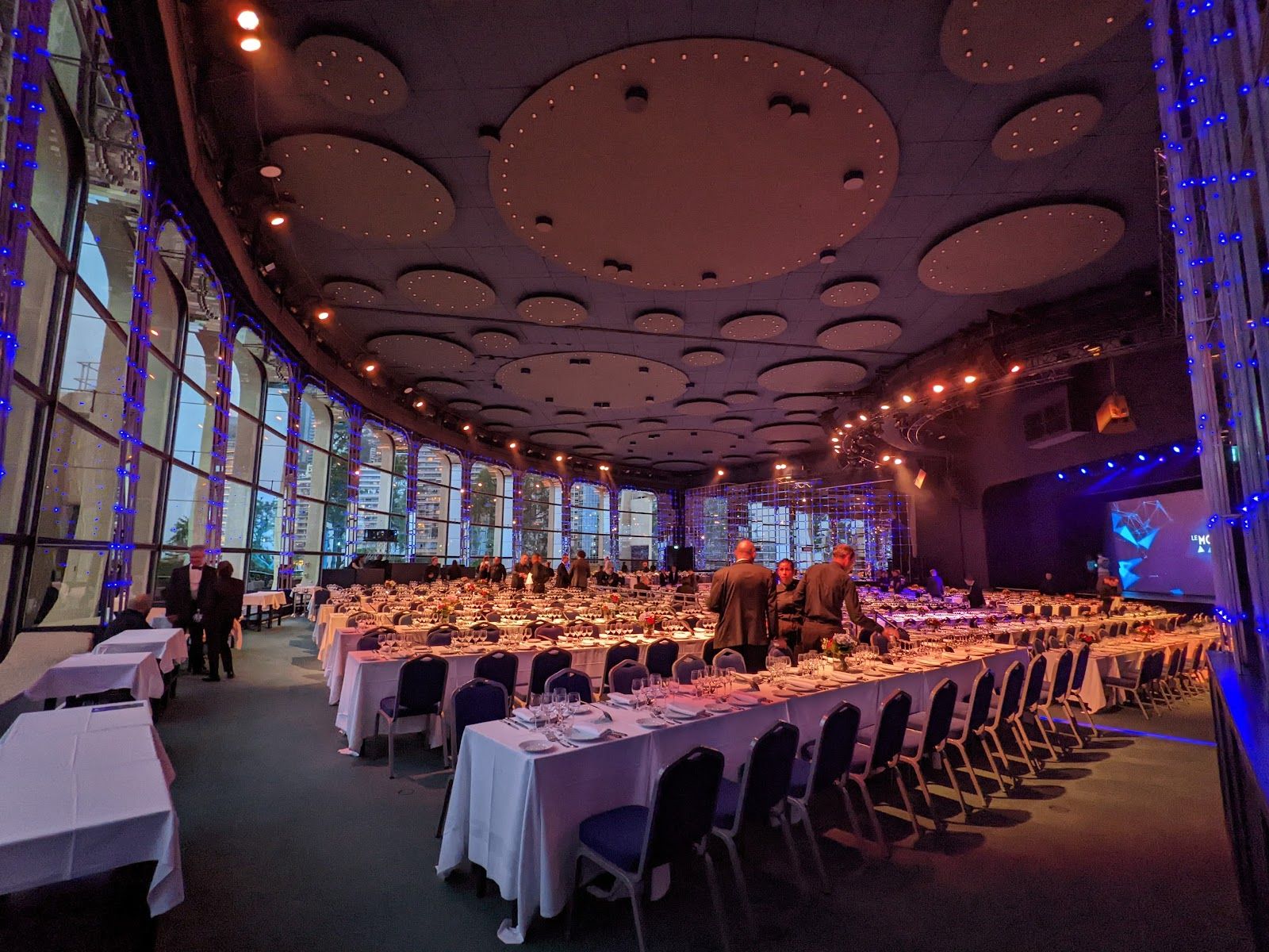 The Salle des Étoiles at Monte-Carlo Sporting set with long tables for a gala dinner, with a curved wall of windows