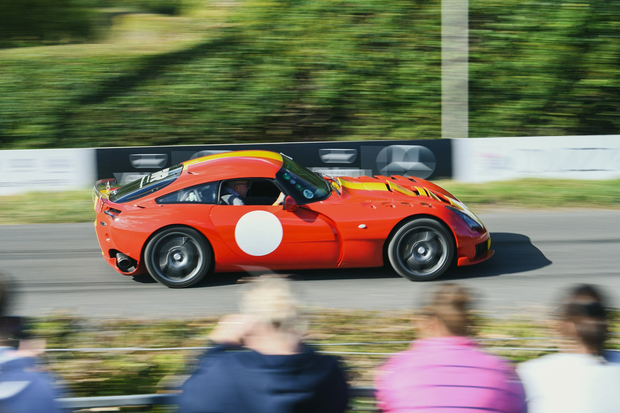 Goodwood Revival cars and crowd (Red sports car racing on a track with spectators.)