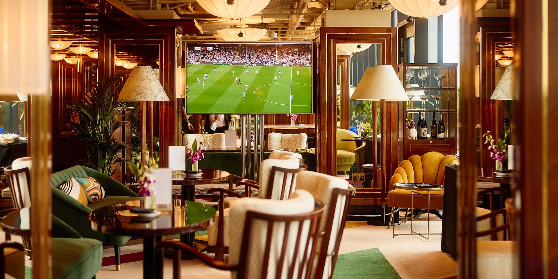 Guests' lounge at The Sky Deck with armchairs and a large screen showing a football match
