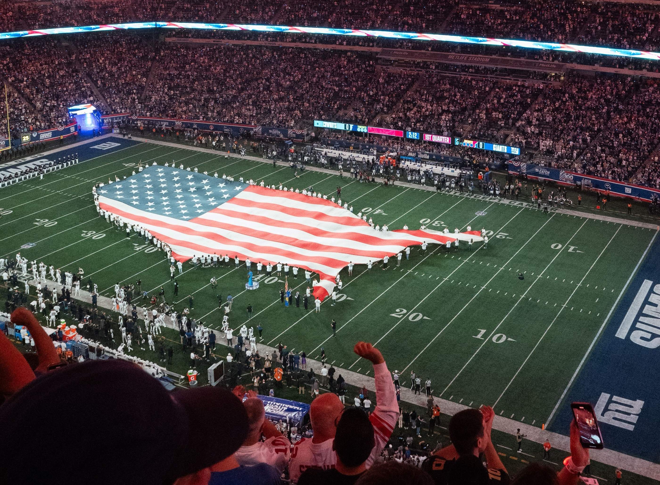 A giant American flag held across an American football field before kick-off