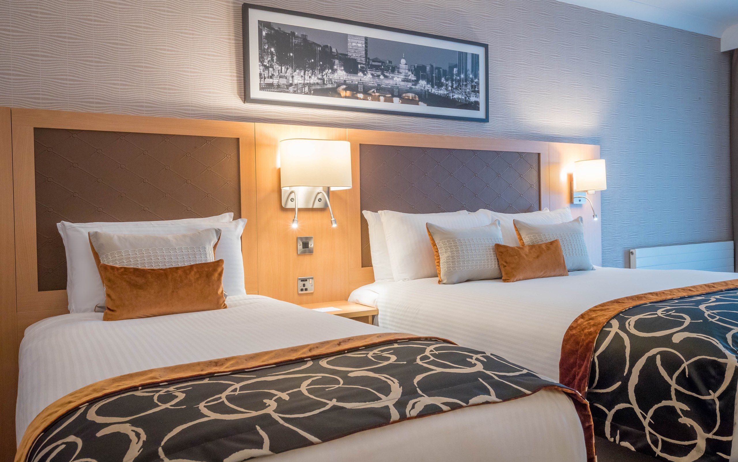 Two beds side by side beneath a framed black-and-white city print