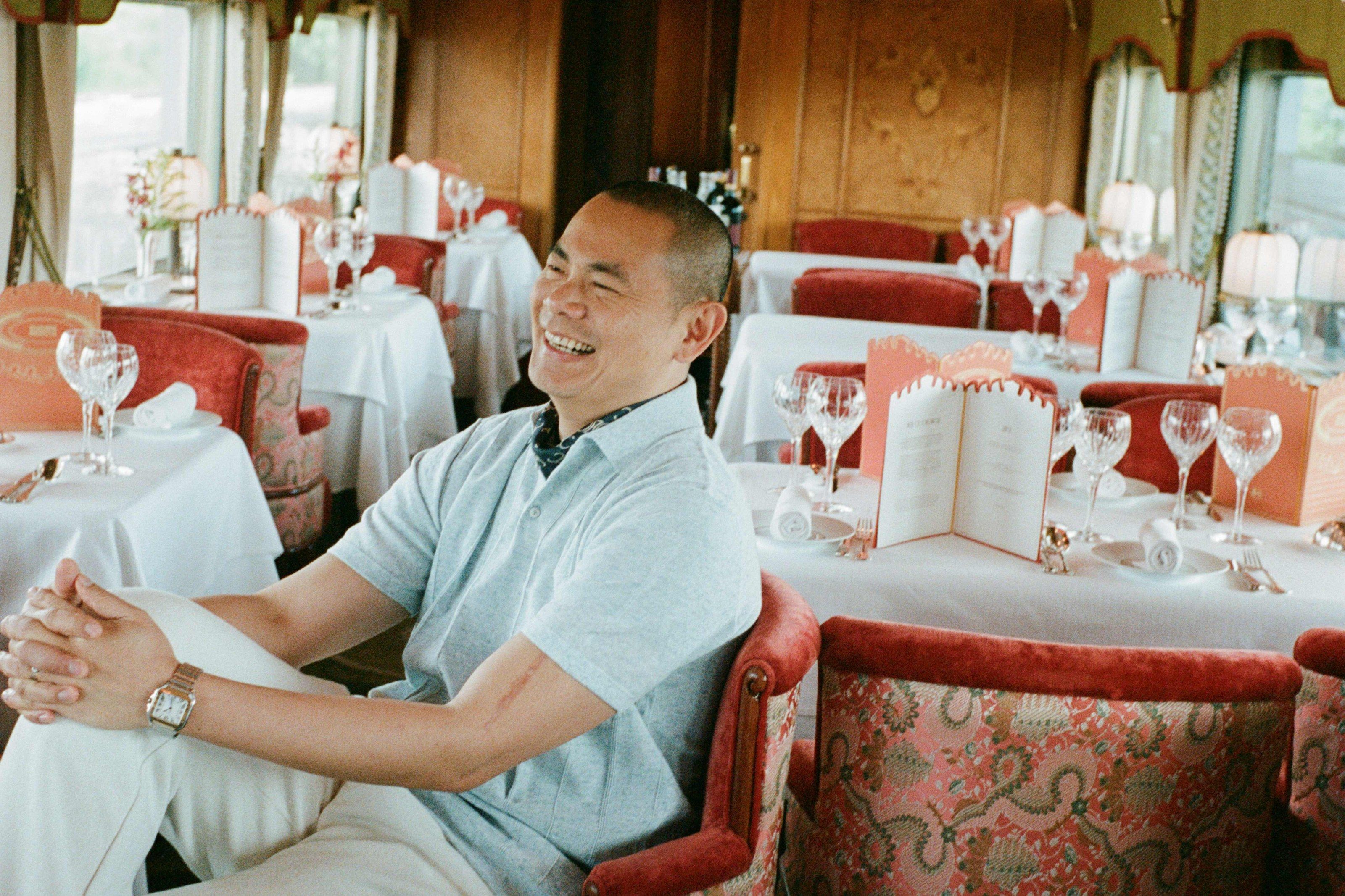 Chef André Chiang sitting in the Malaya dining car, with tables laid for lunch behind him.