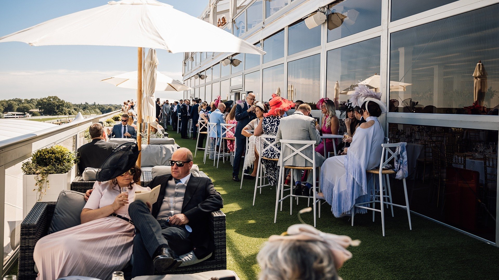 Ladies in colourful headpieces on The Lawn Club hospitality terrace at Royal Ascot