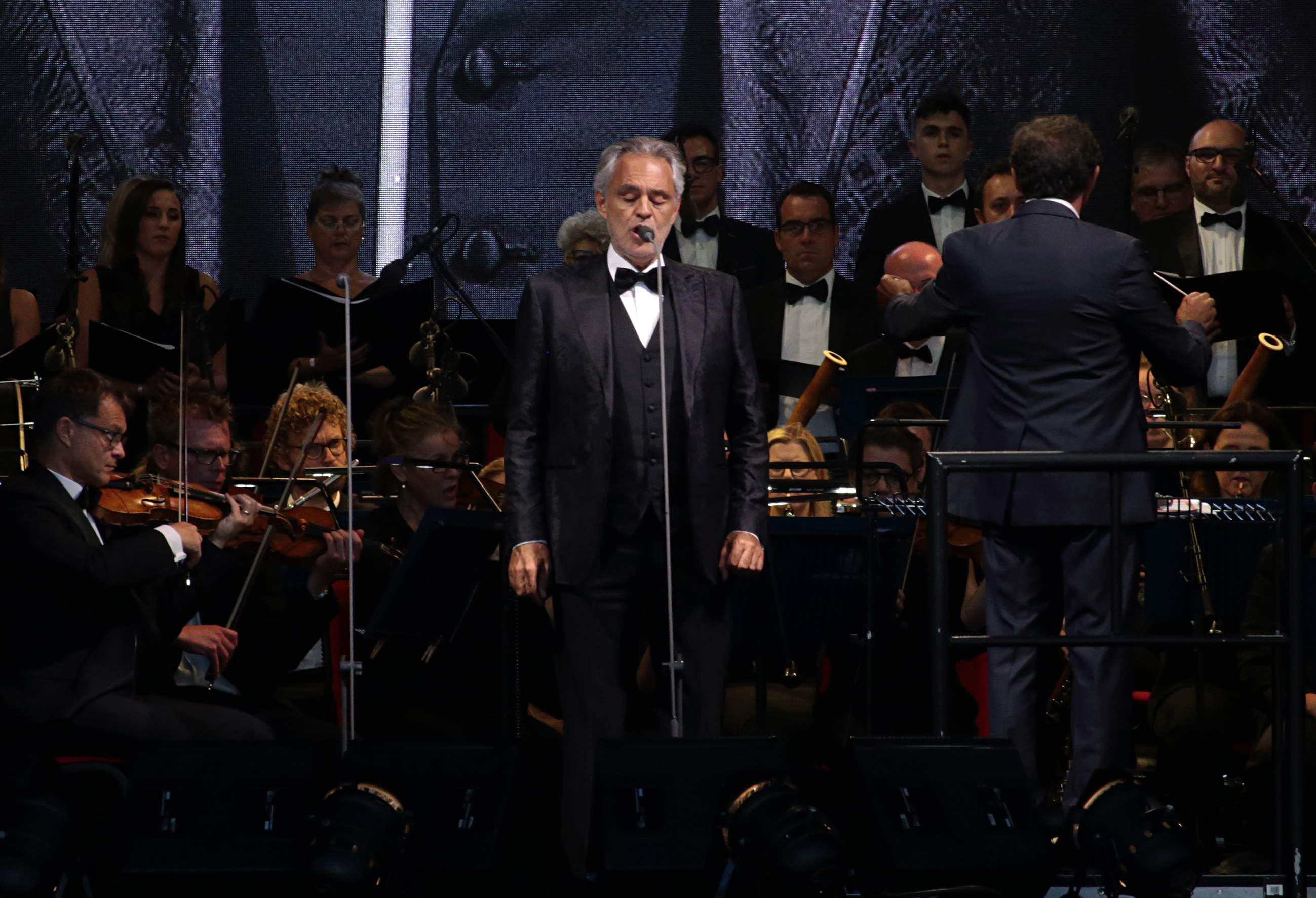 Andrea Bocelli singing with orchestra and choir behind him