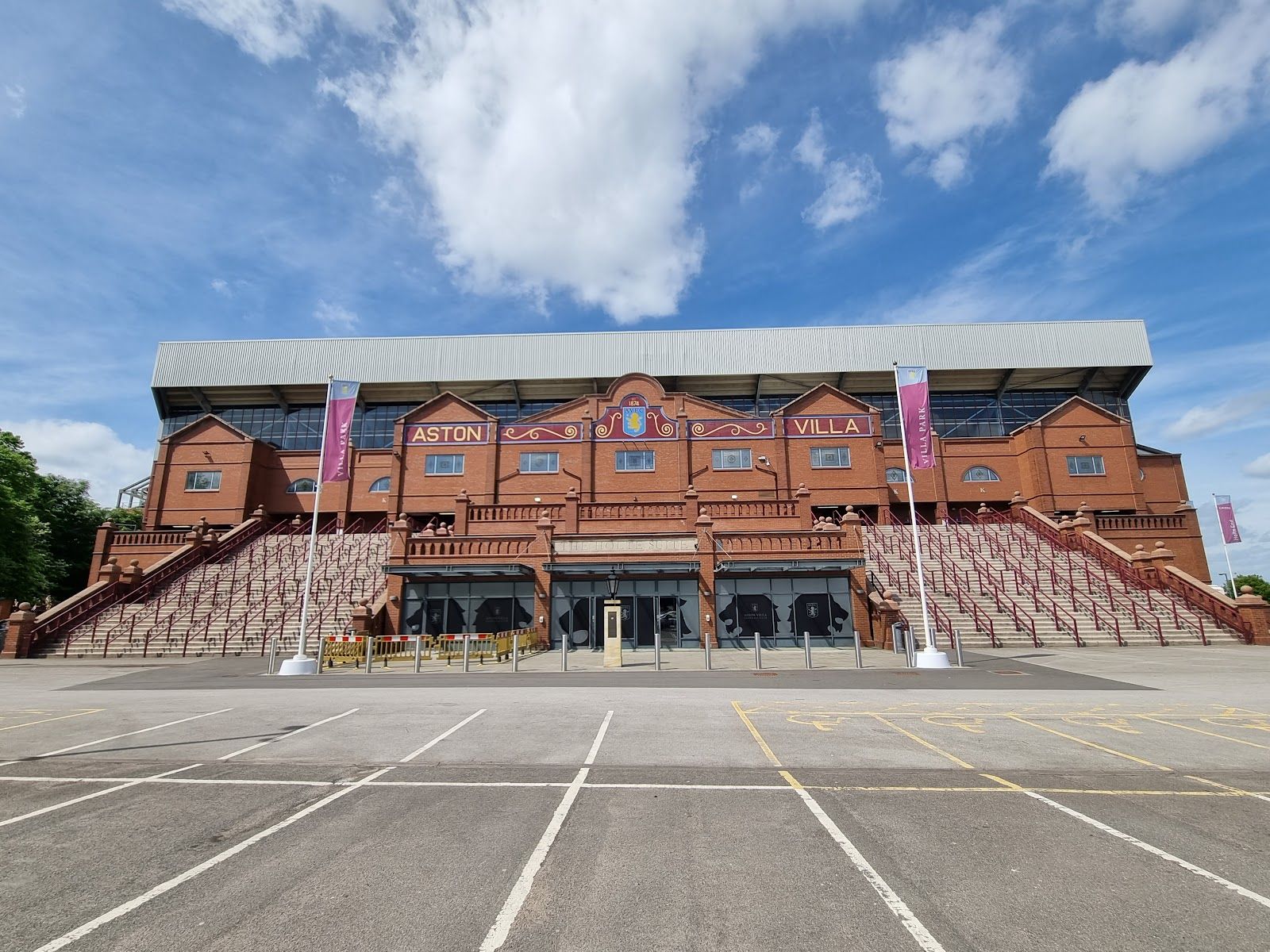 The red-brick Holte End facade at Villa Park with Aston Villa lettering above the entrances