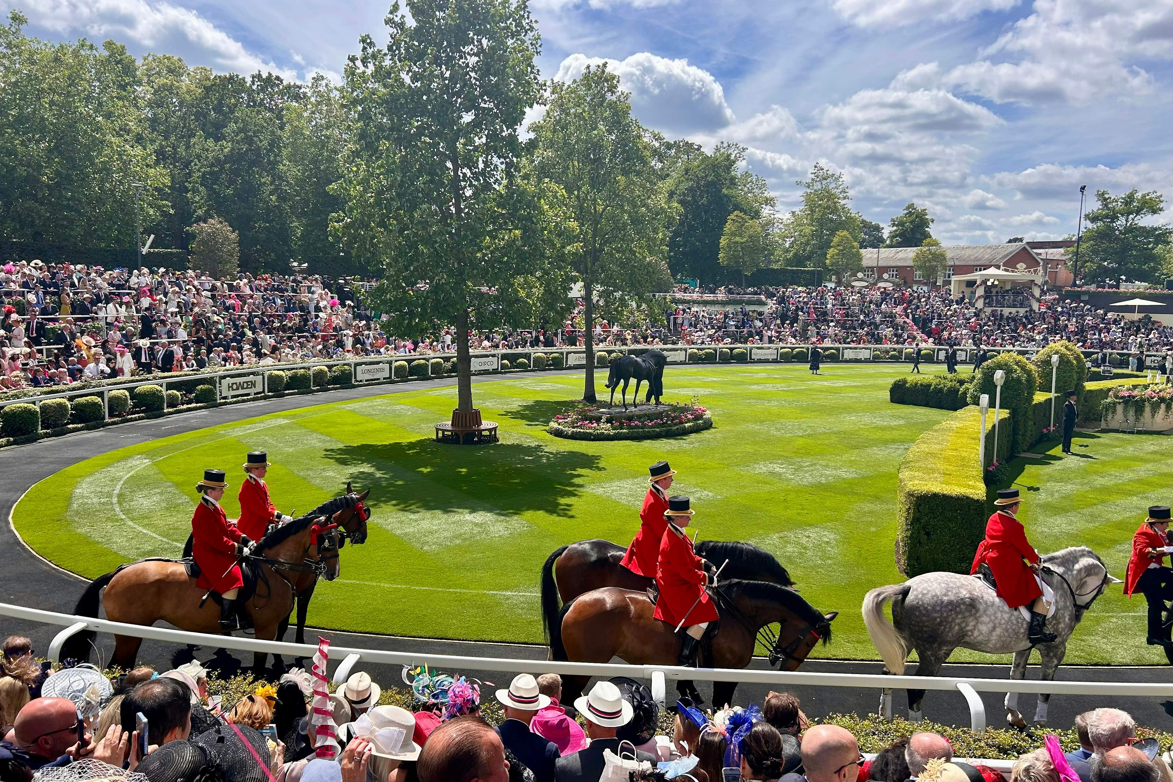 Ceremonial outriders and the hatted crowd around the parade ring at Royal Ascot