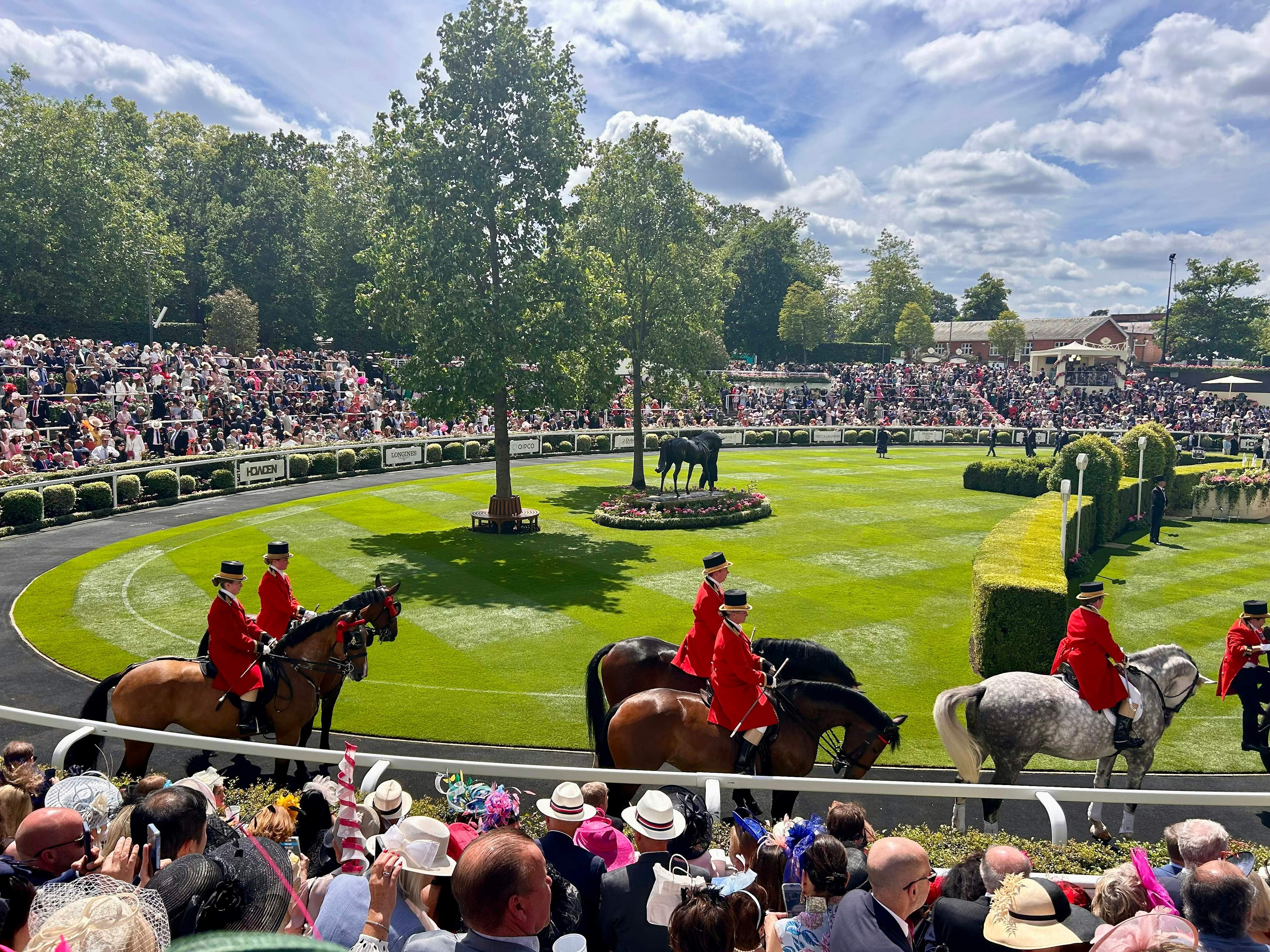 Ceremonial outriders and the hatted crowd around the parade ring at Royal Ascot