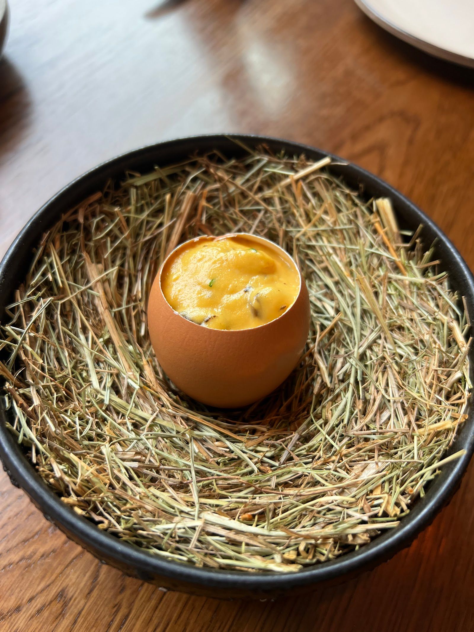 A dish served in an eggshell on a nest of hay at HIDE