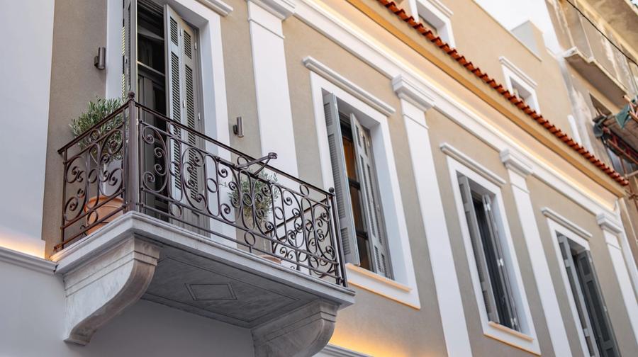 Restored neoclassical facade of Emerald Hotel Athens on Perikleous Street — arched doorways and ornate plasterwork in the historic centre