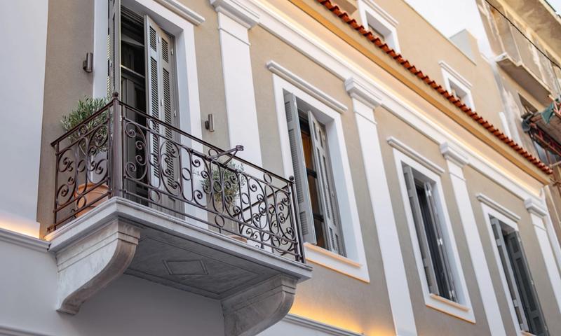 Restored neoclassical facade of Emerald Hotel Athens on Perikleous Street — arched doorways and ornate plasterwork in the historic centre