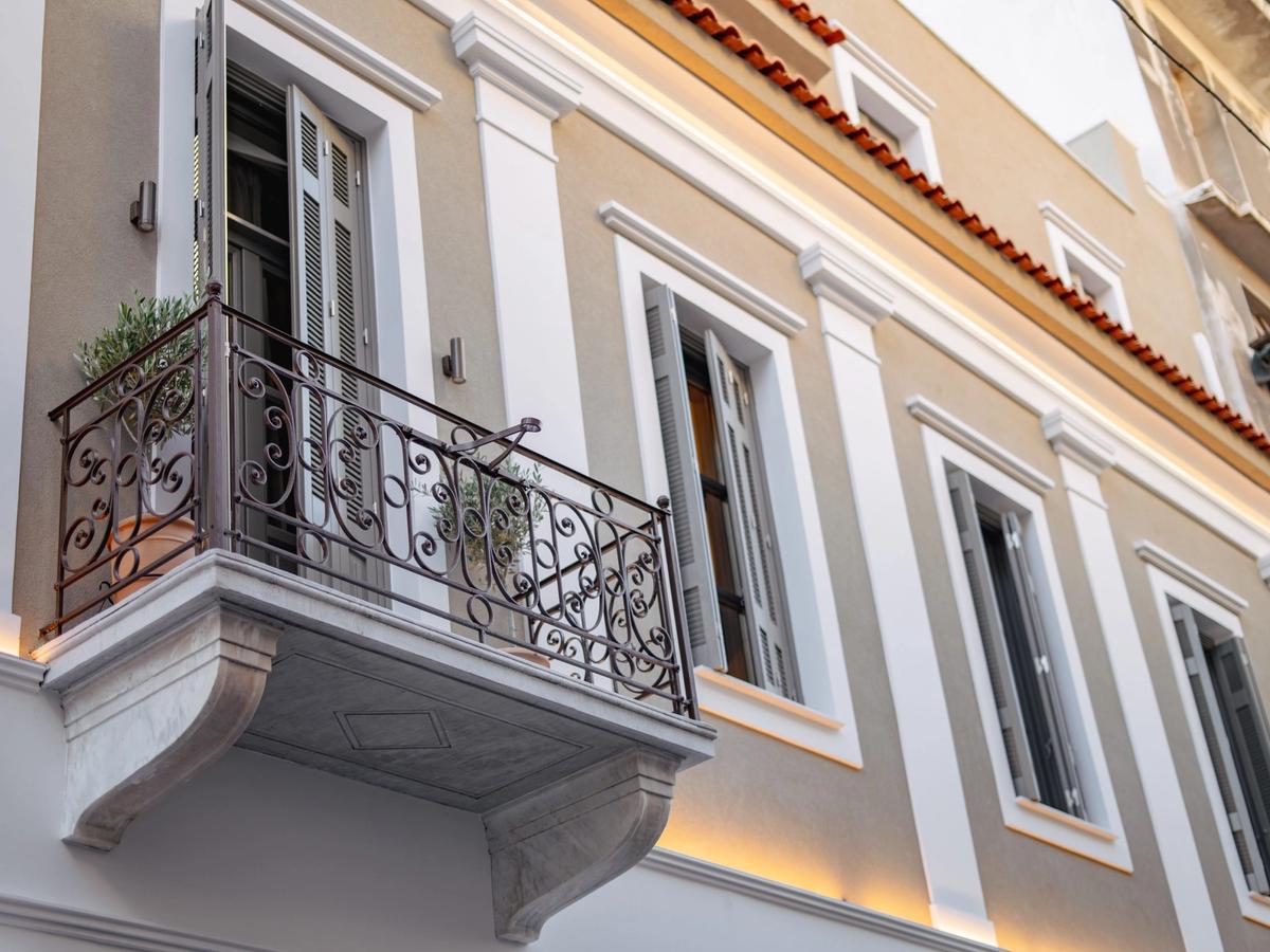 Restored neoclassical facade of Emerald Hotel Athens on Perikleous Street — arched doorways and ornate plasterwork in the historic centre
