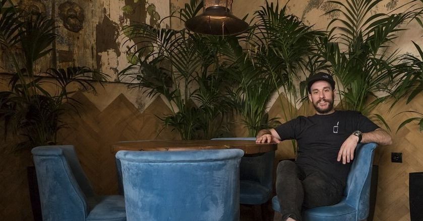 Nikos Bakoulis seated in a blue armchair at The Clumsies